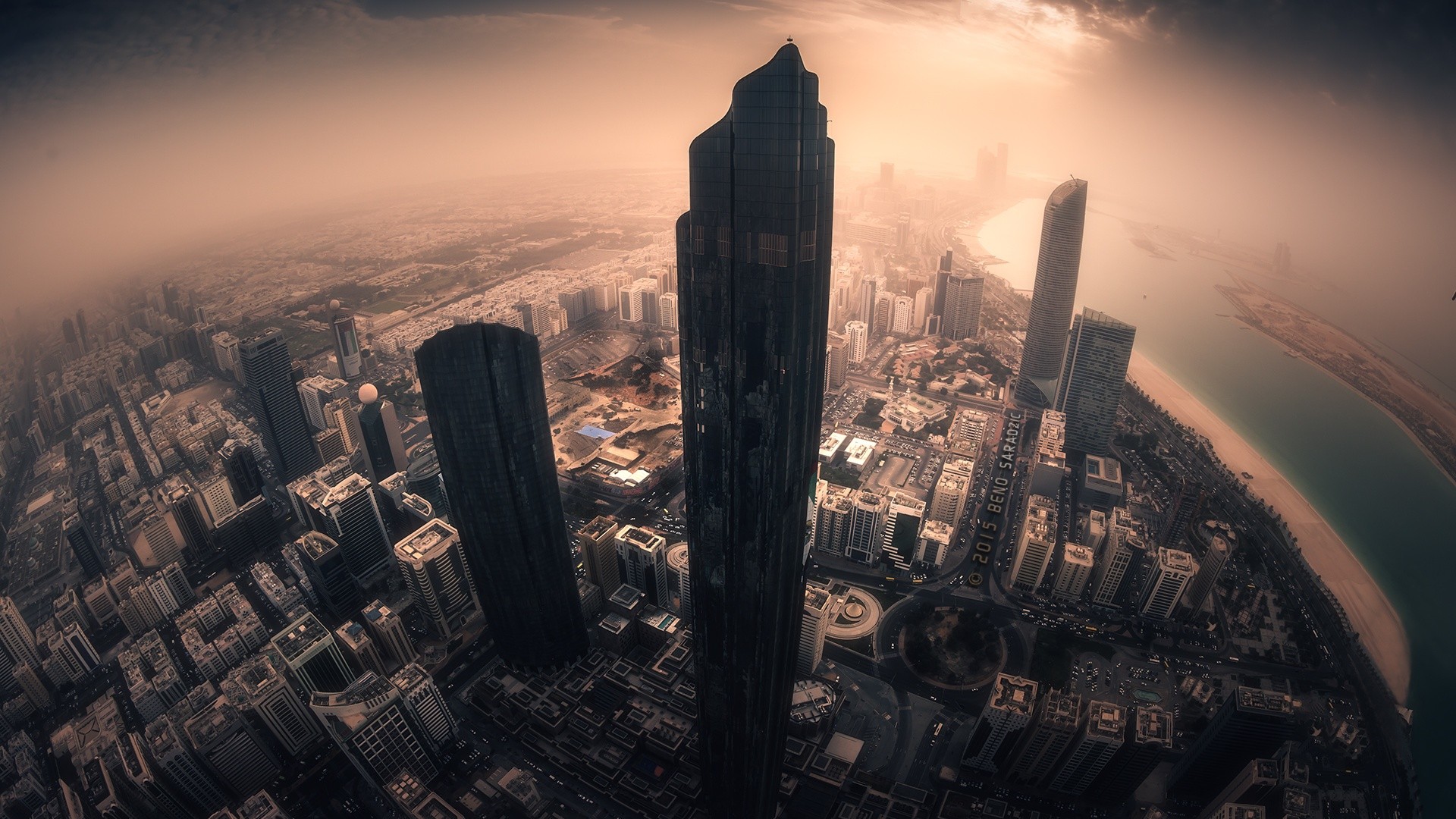 Aerial view of a modern city skyline with skyscrapers and a bay HD Wallpaper