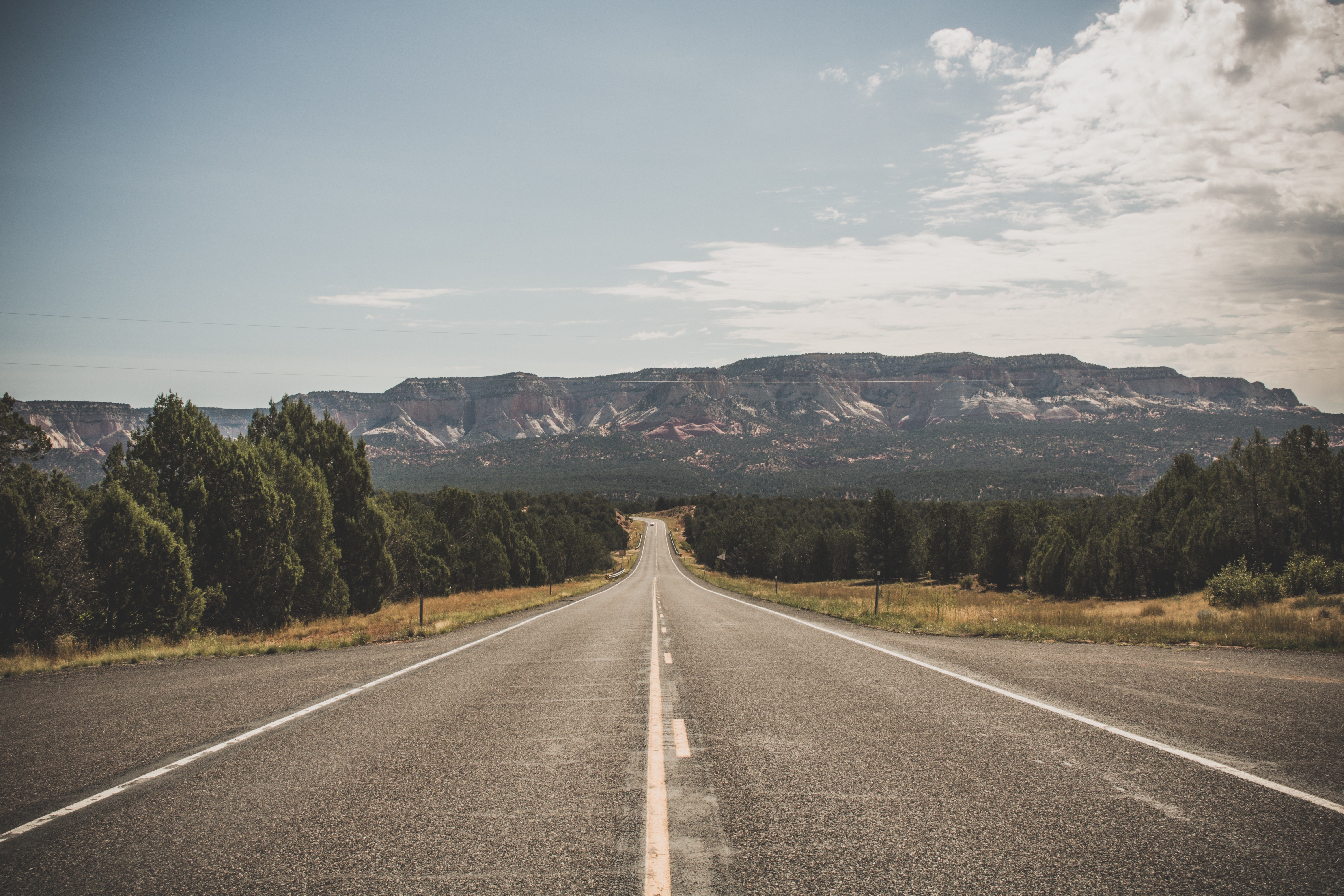 Empty highway leading to distant mountains HD Wallpaper