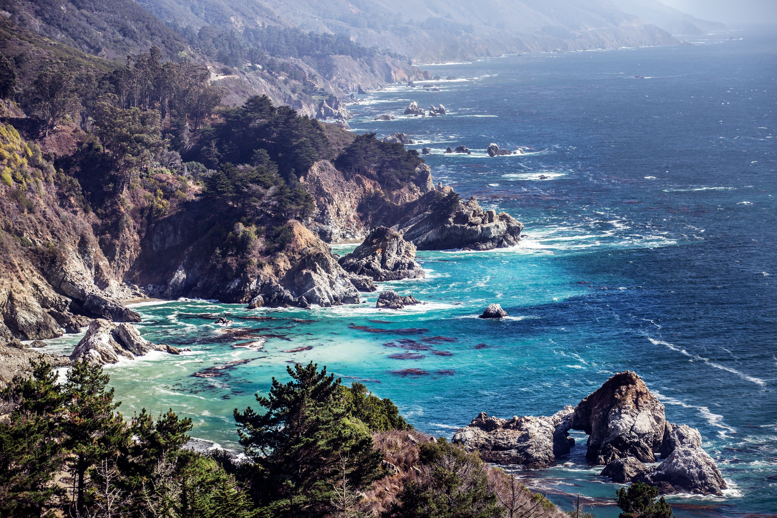 Rocky coastline with turquoise water and trees HD Wallpaper