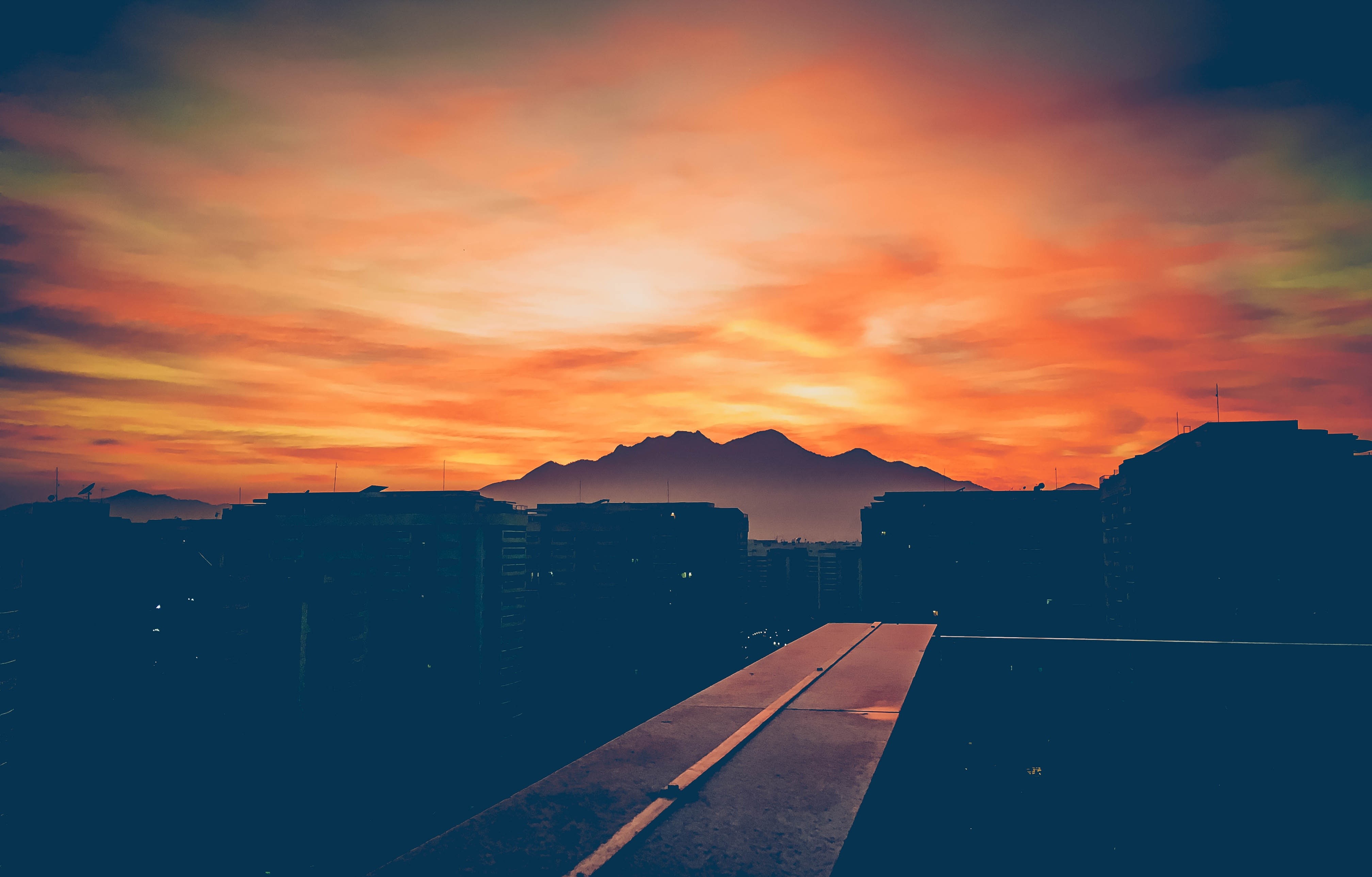Sunset over city buildings and mountains HD Wallpaper