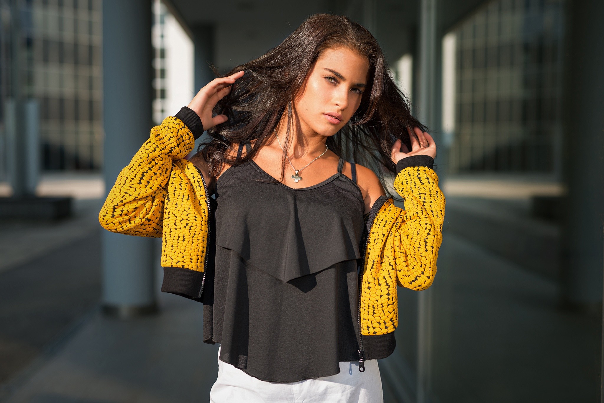 Woman with hands in hair wearing yellow jacket HD Wallpaper