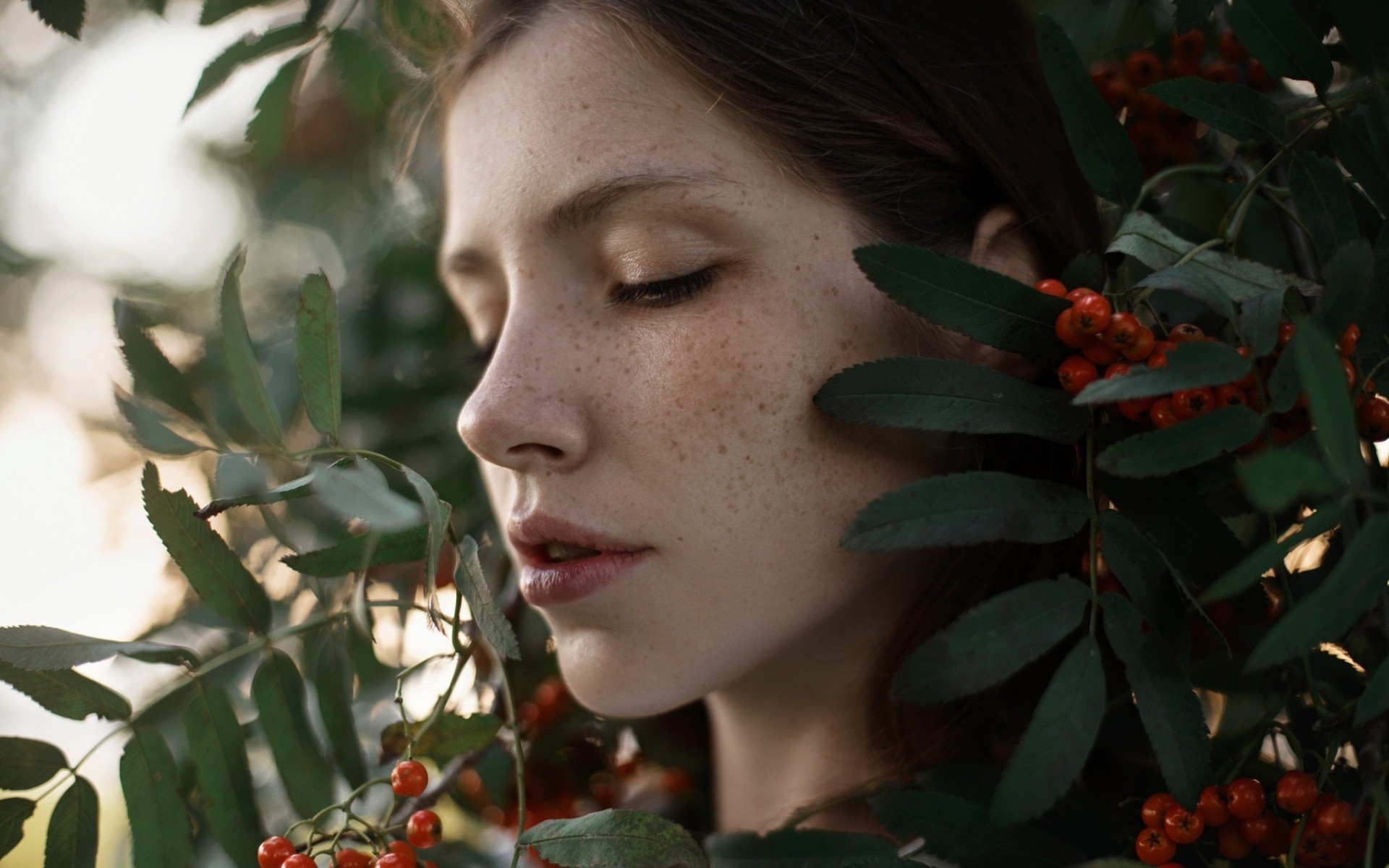 Woman with freckles among leaves and berries HD Wallpaper