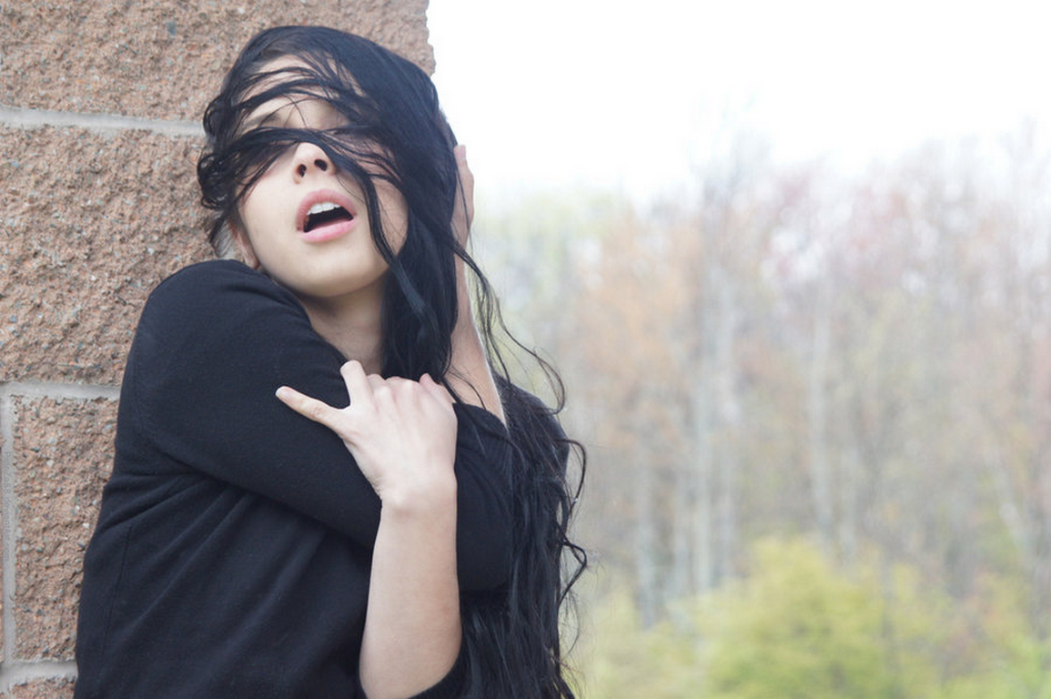 Woman with hair covering face leaning against wall HD Wallpaper