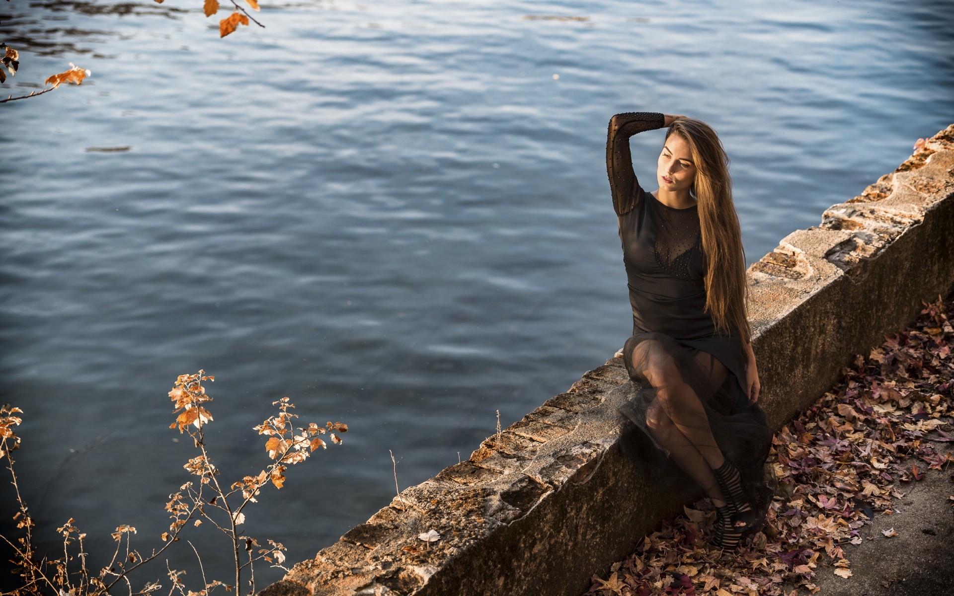 Woman in black dress sitting by the water HD Wallpaper
