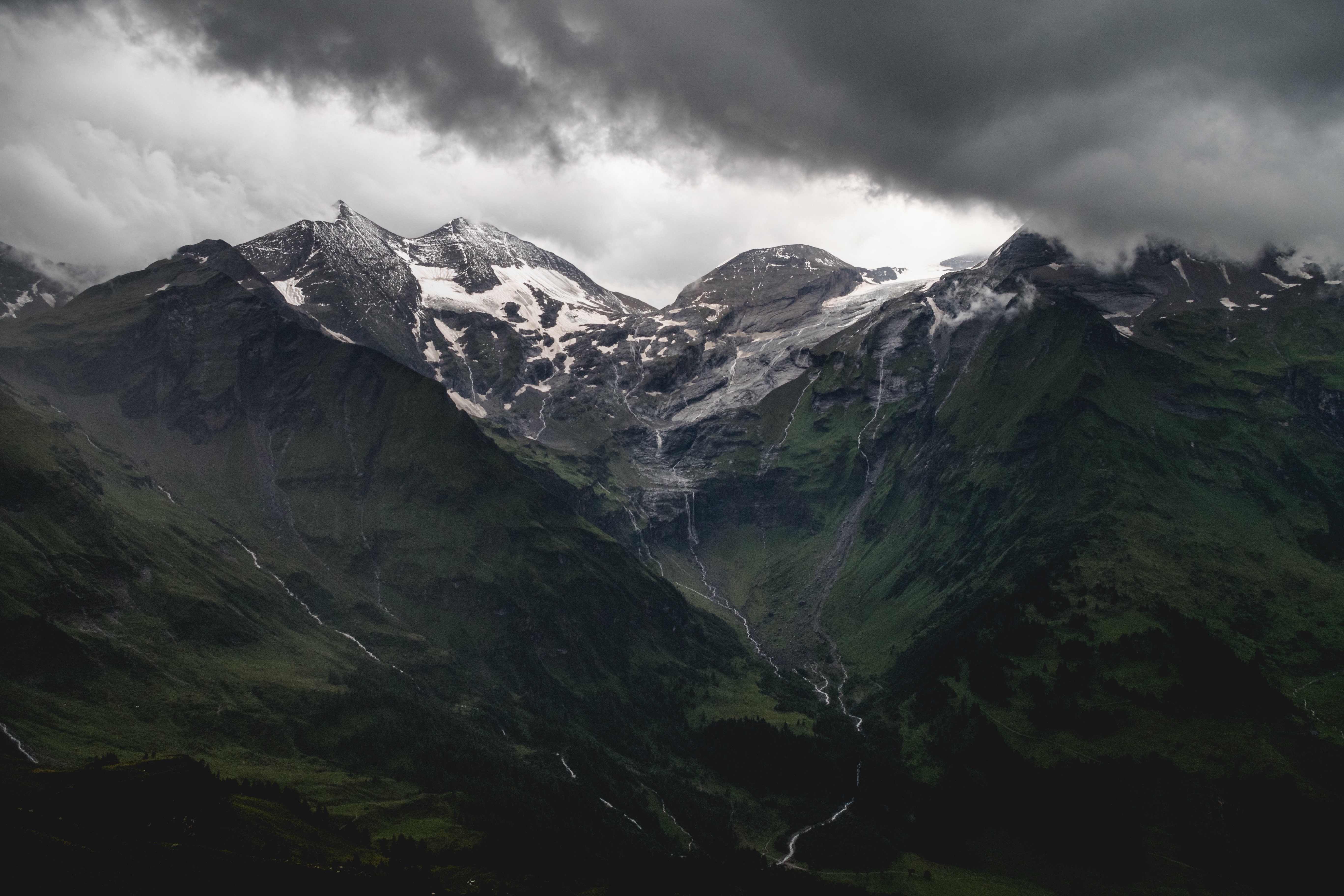 Snow-capped mountains under dark clouds HD Wallpaper