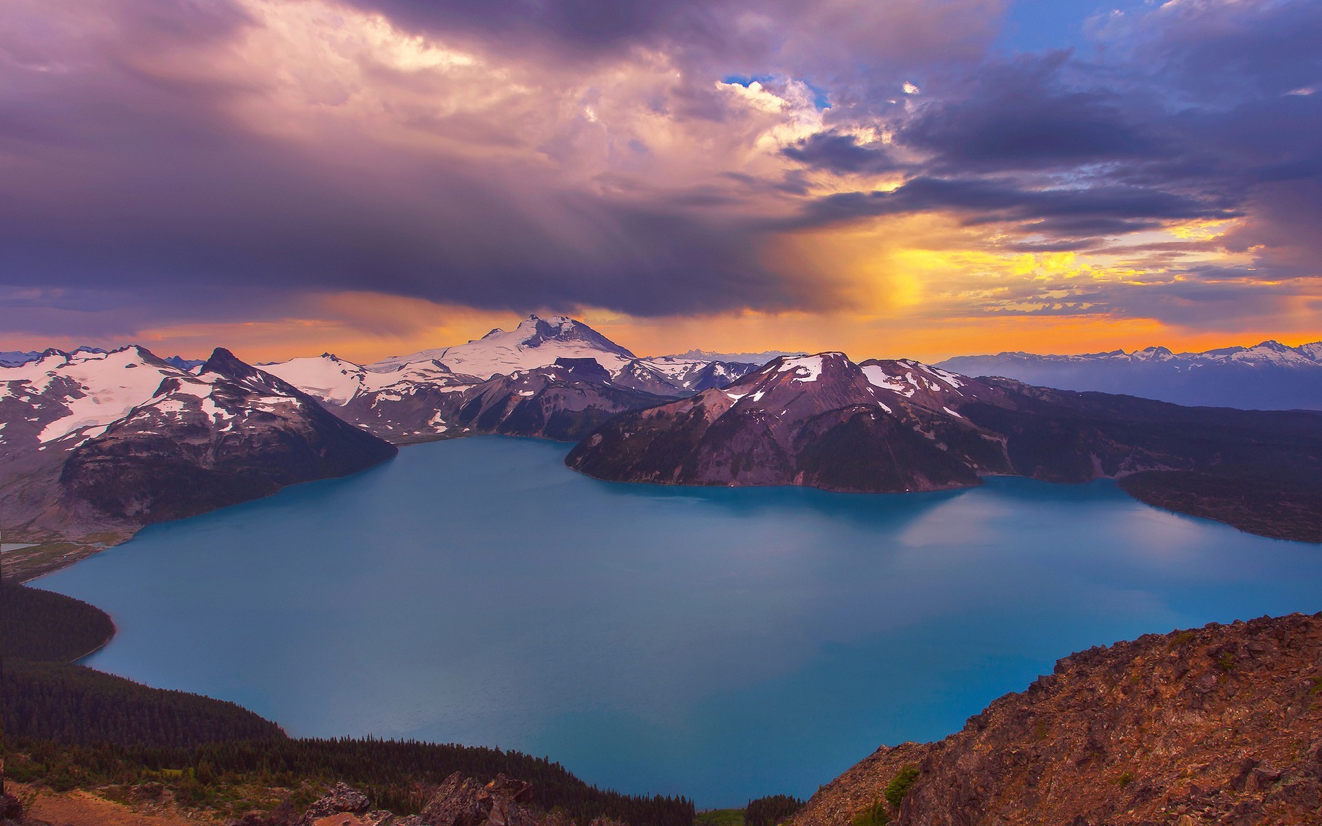 Turquoise lake surrounded by snow-capped mountains at sunset HD Wallpaper