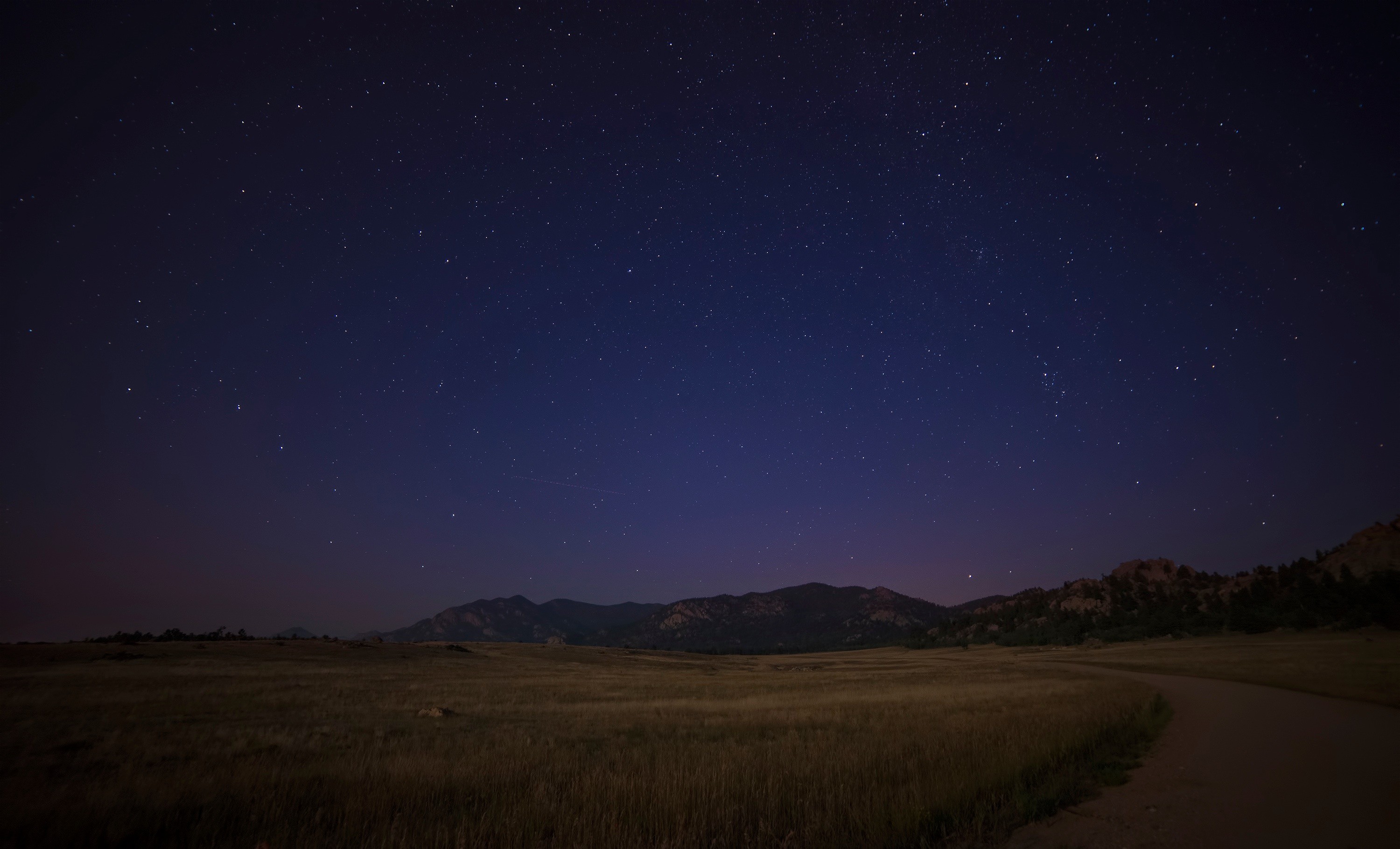 Night sky over mountains and a field HD Wallpaper