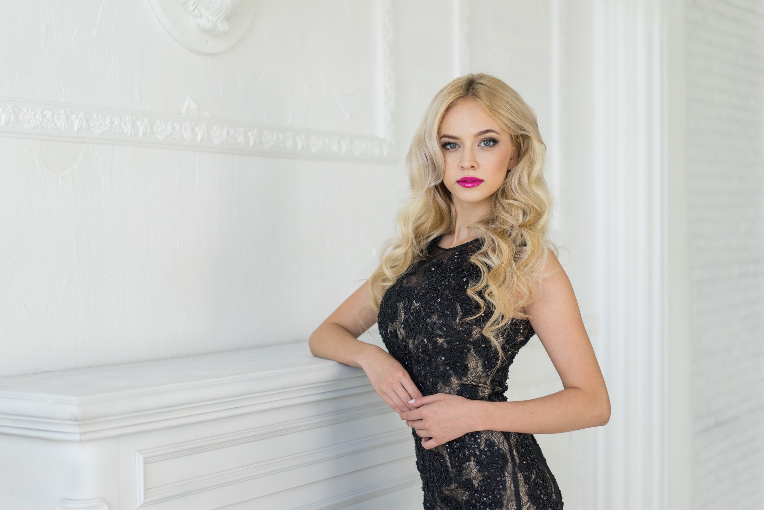Blonde woman in a black dress posing by a fireplace HD Wallpaper