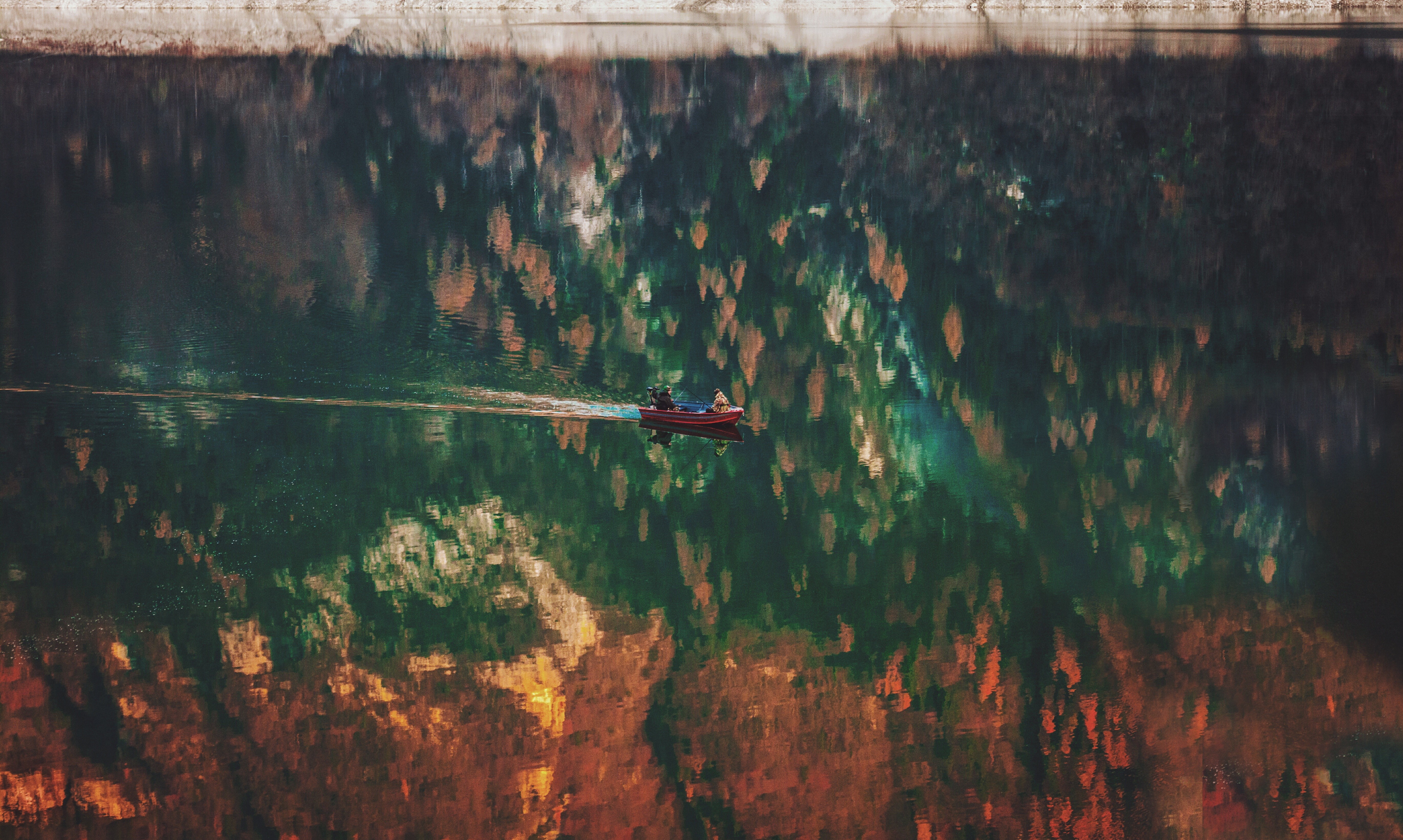Boat on a reflective lake with autumn foliage HD Wallpaper