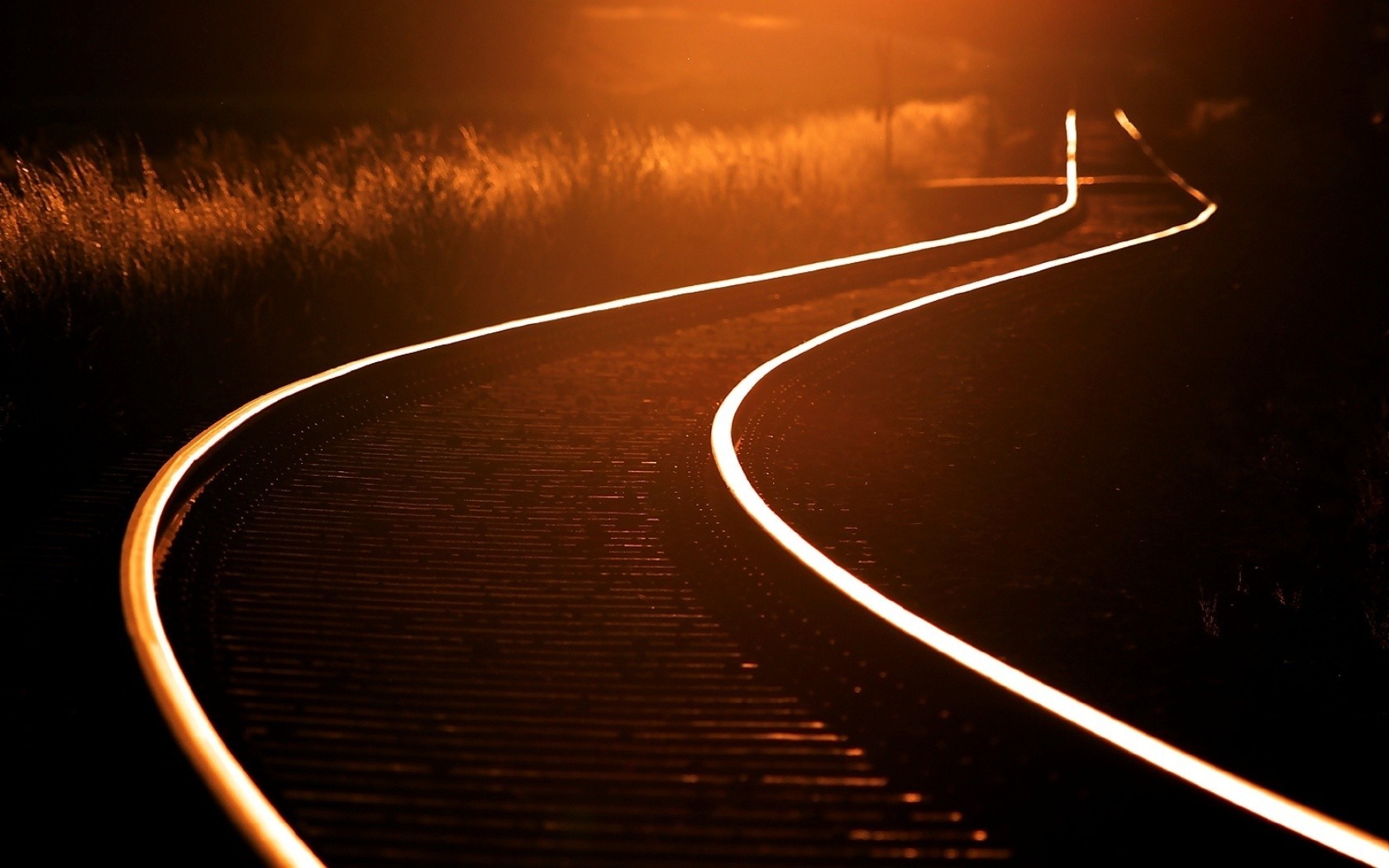 Railway tracks curving into the distance with golden light HD Wallpaper