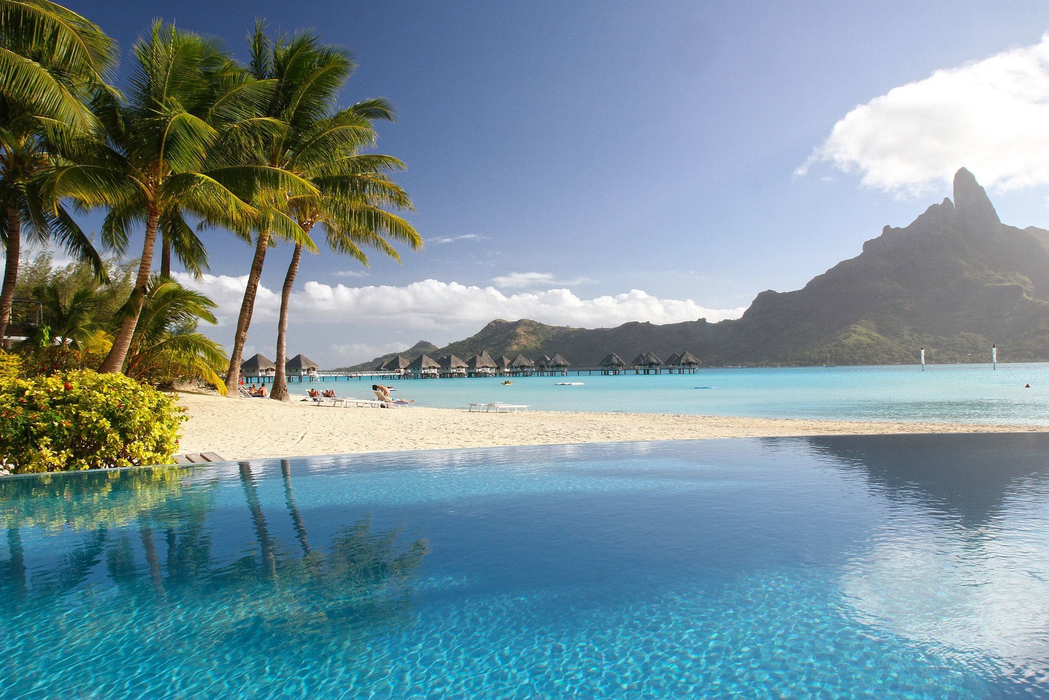 Tropical beach with overwater bungalows and a mountain HD Wallpaper