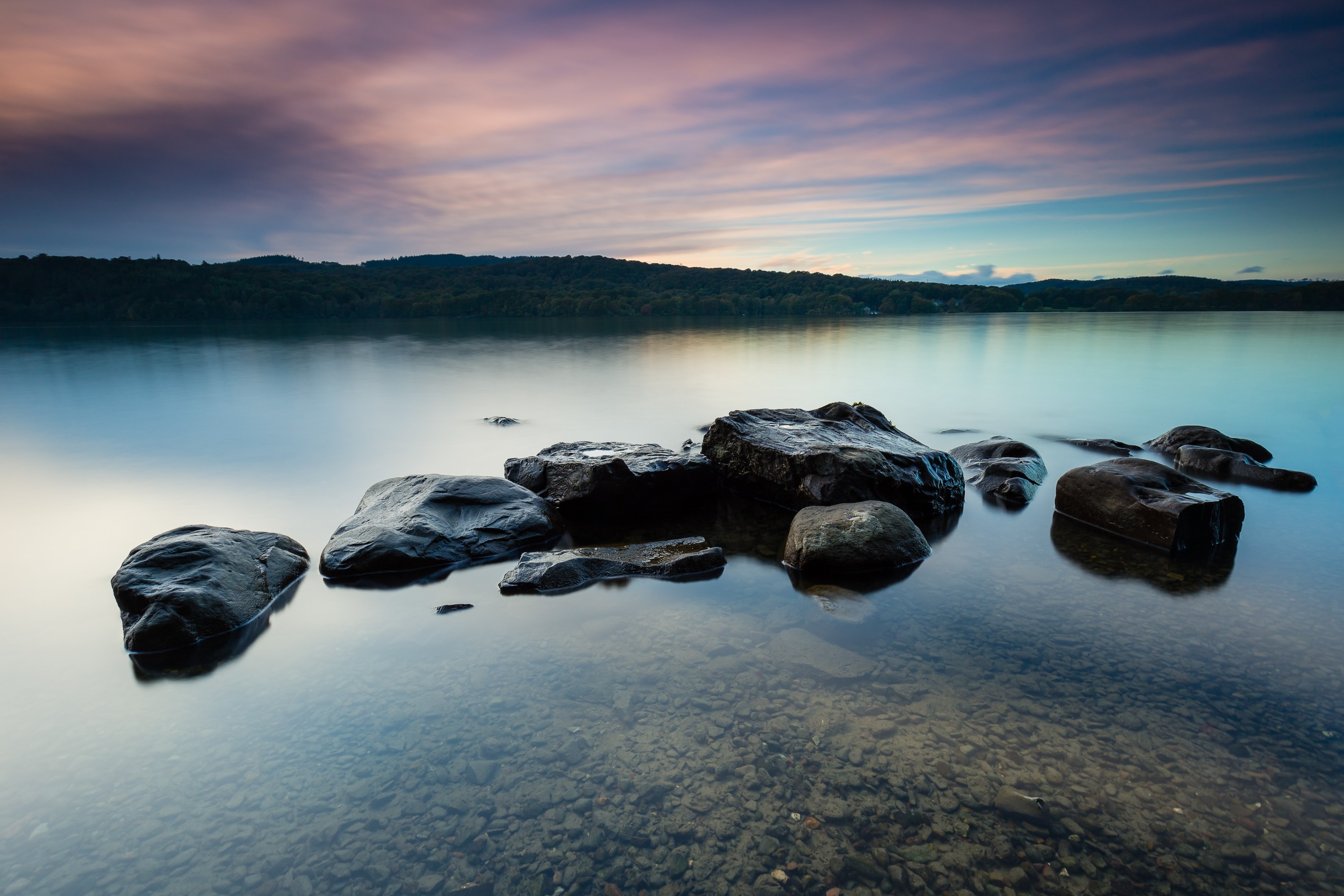 Rocks in a calm lake at sunset HD Wallpaper
