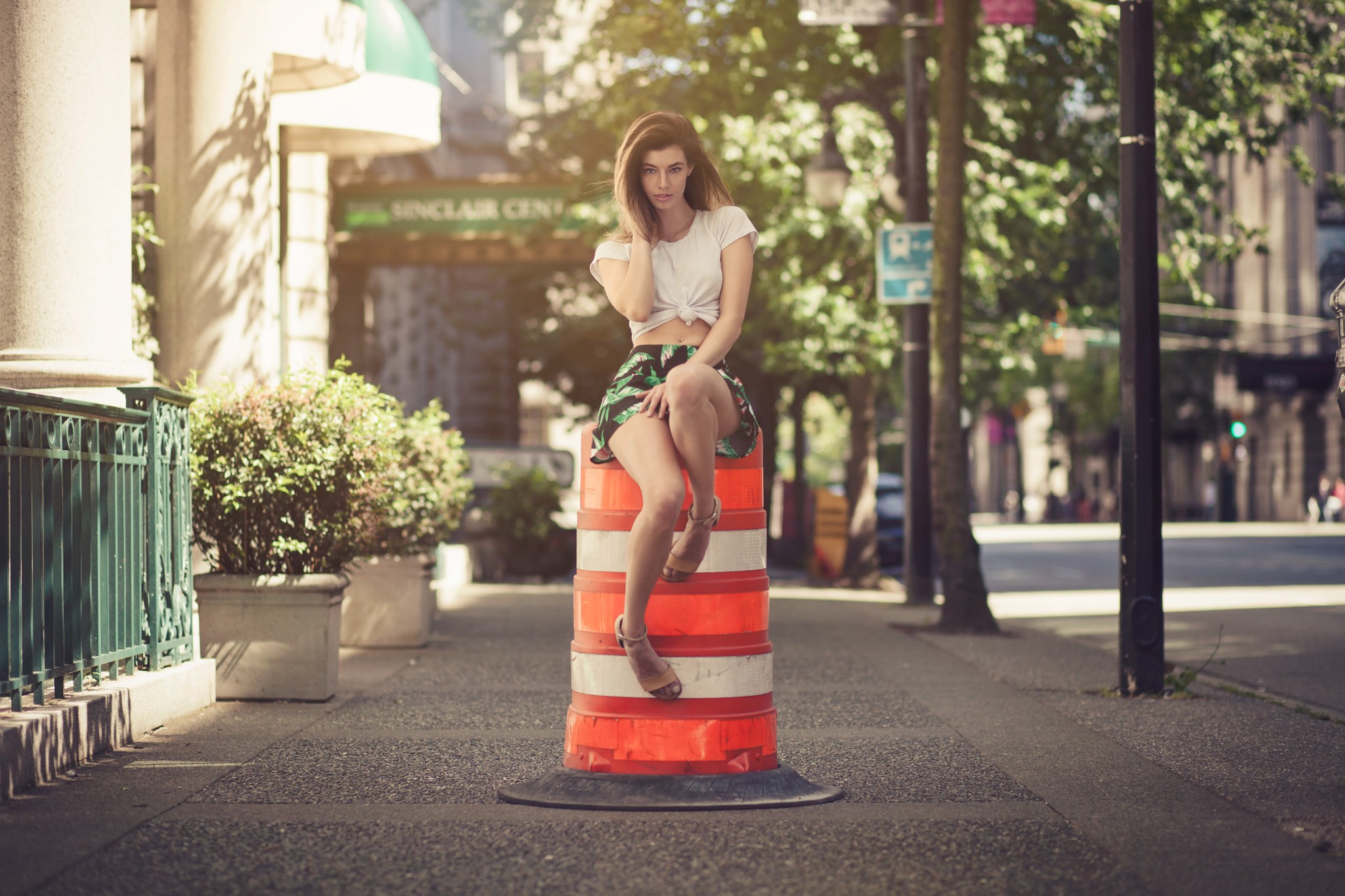 Woman sitting on a traffic barrel outdoors HD Wallpaper