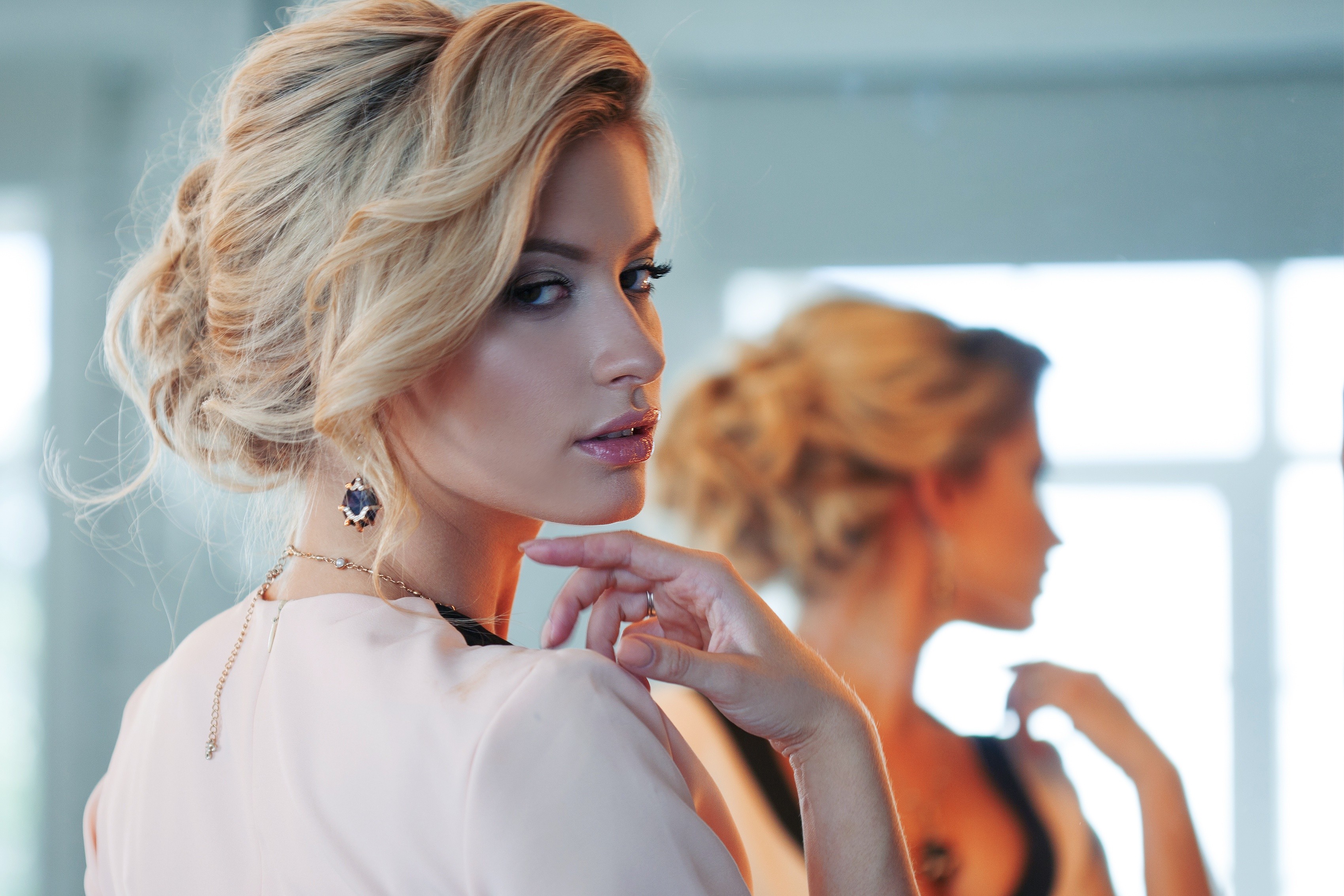 Woman with blonde hair in a bun looking in a mirror HD Wallpaper