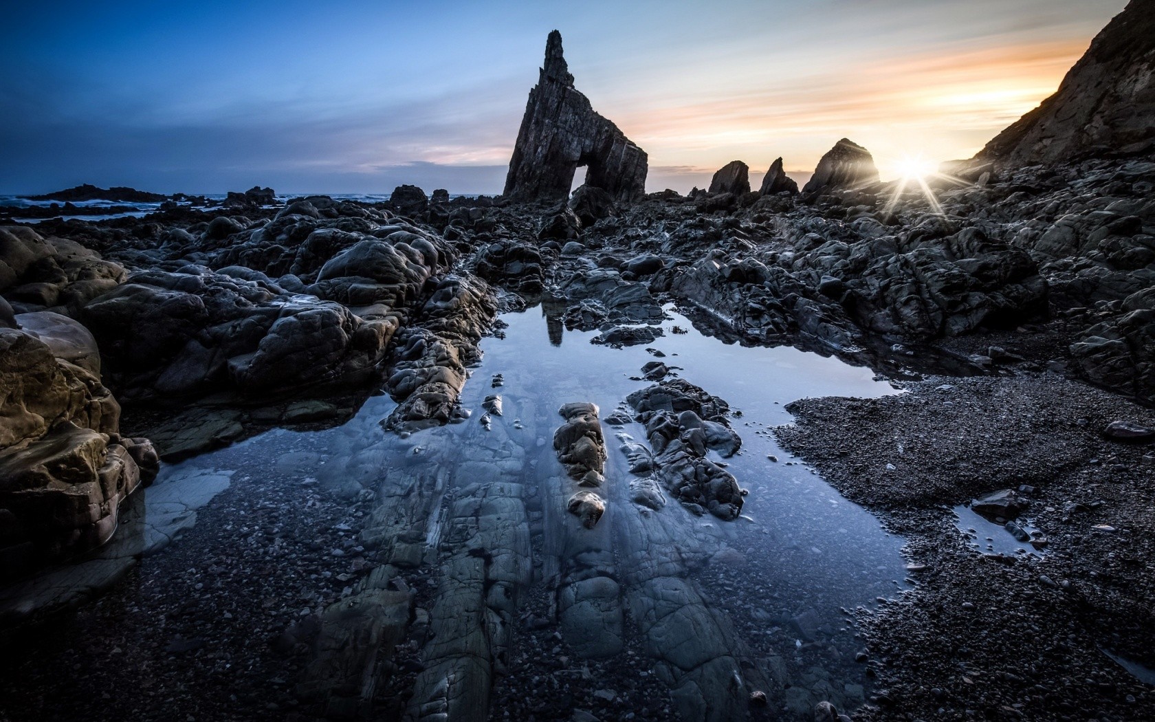 Rocky coastline with natural arch at sunset HD Wallpaper