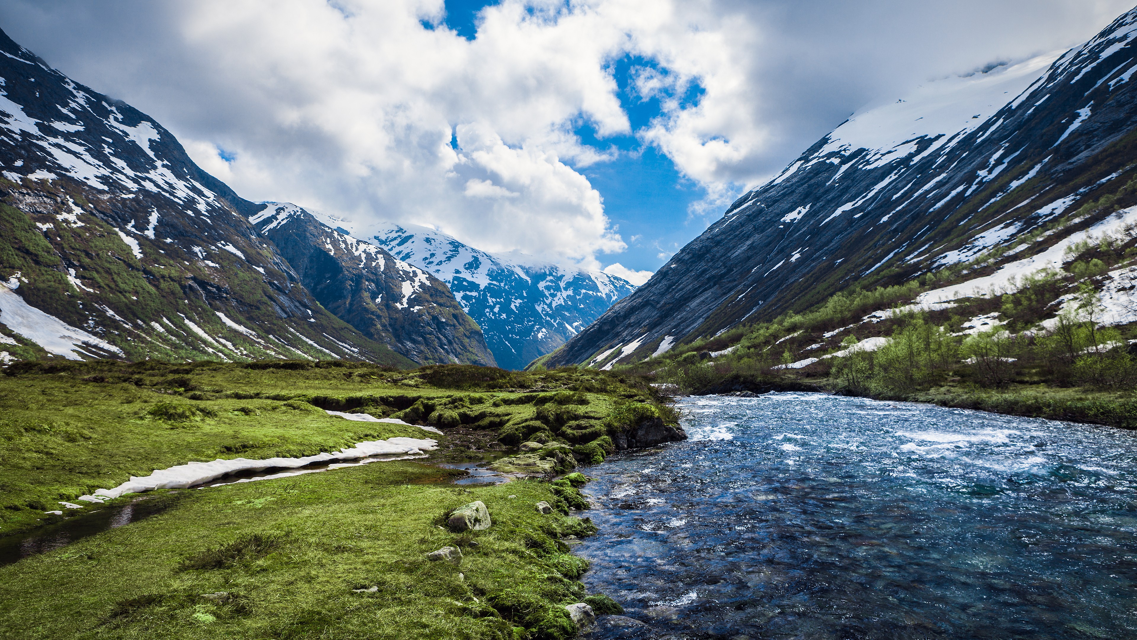 River flowing through a valley with snow-capped mountains HD Wallpaper