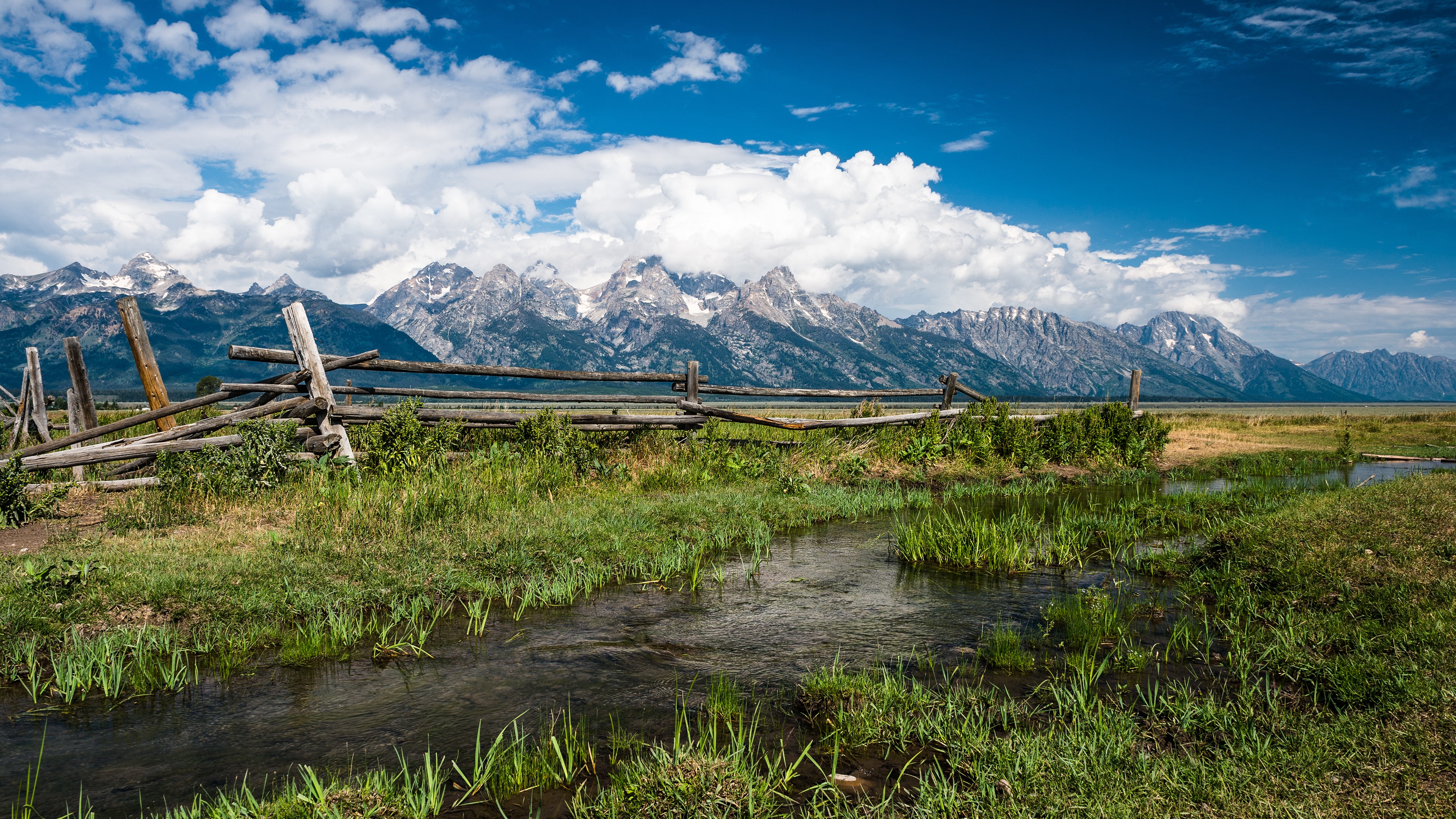 Grand Teton Mountains with a wooden fence and stream HD Wallpaper