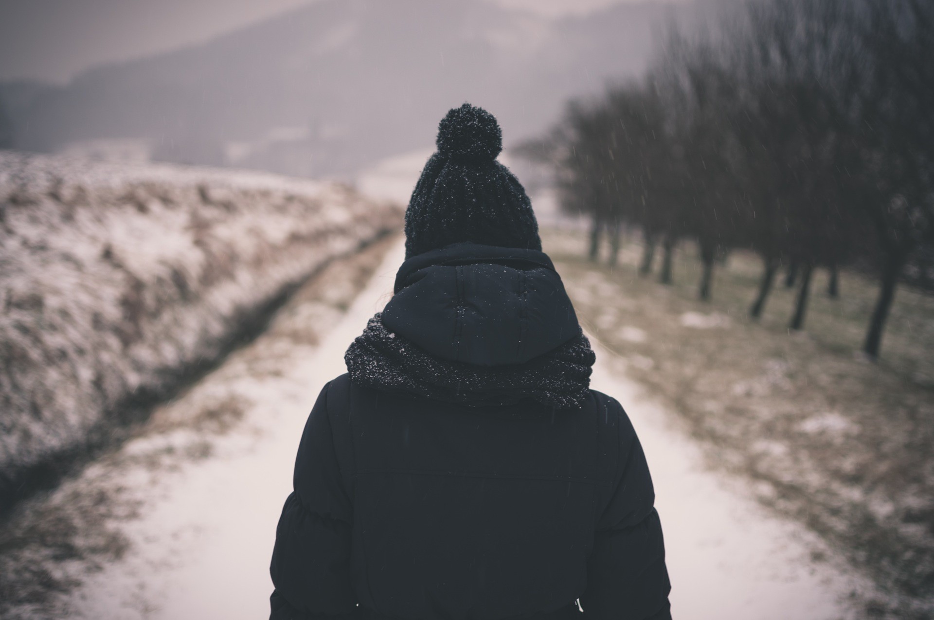 Person in winter coat walking on snowy path HD Wallpaper