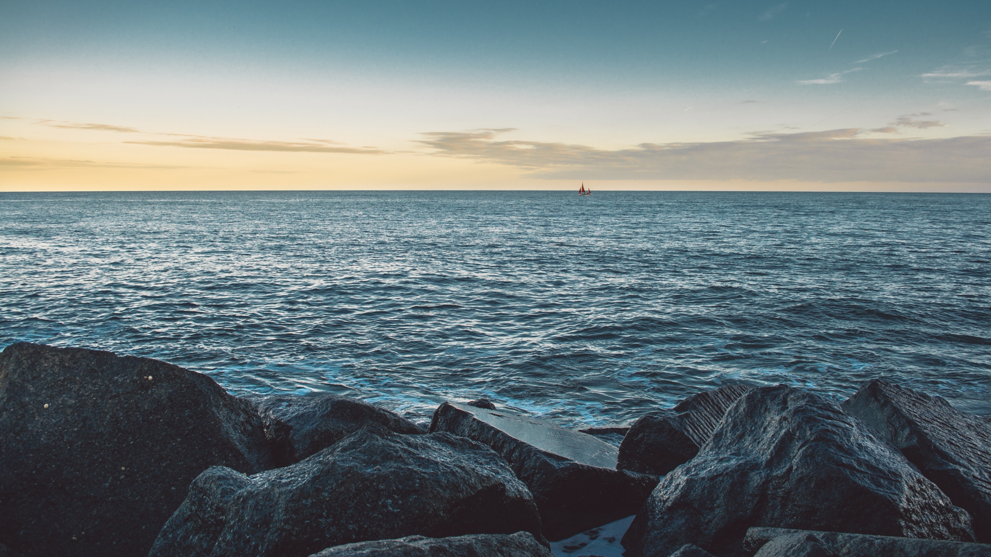 Sailboat on the ocean with rocks in the foreground HD Wallpaper