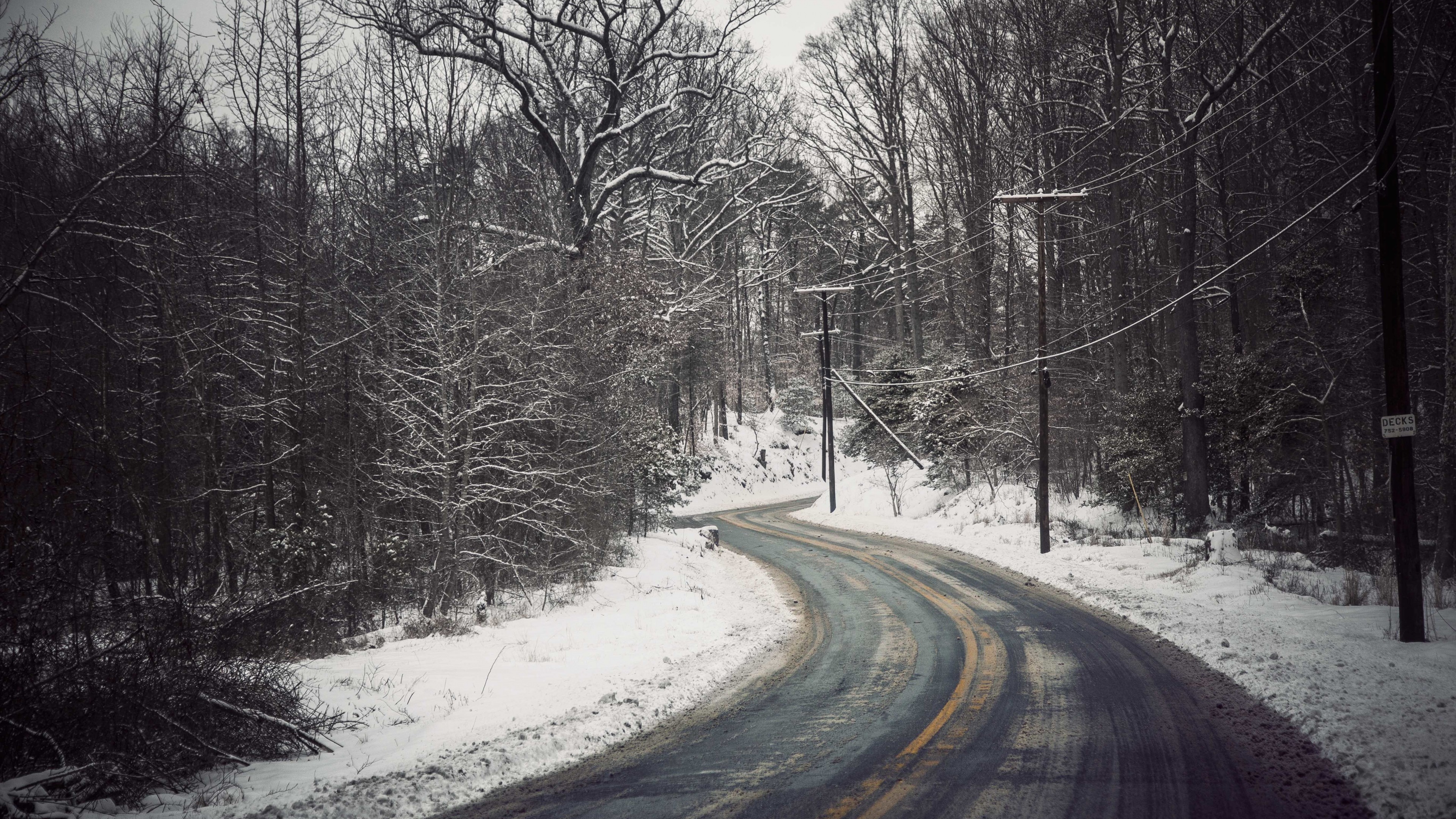 Winding snowy road through a winter forest with power lines HD Wallpaper