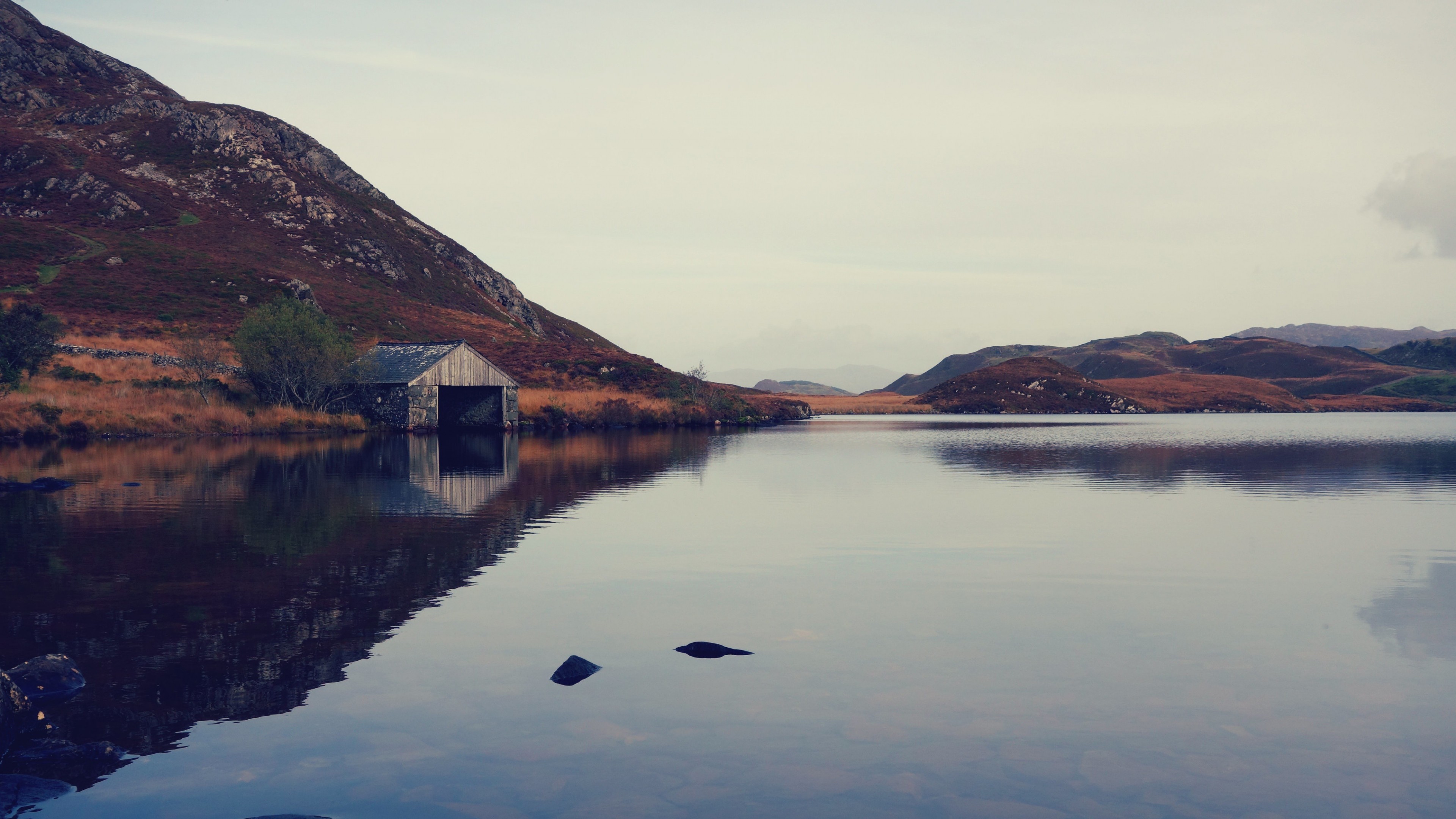 Boathouse on a lake with mountains in the background HD Wallpaper