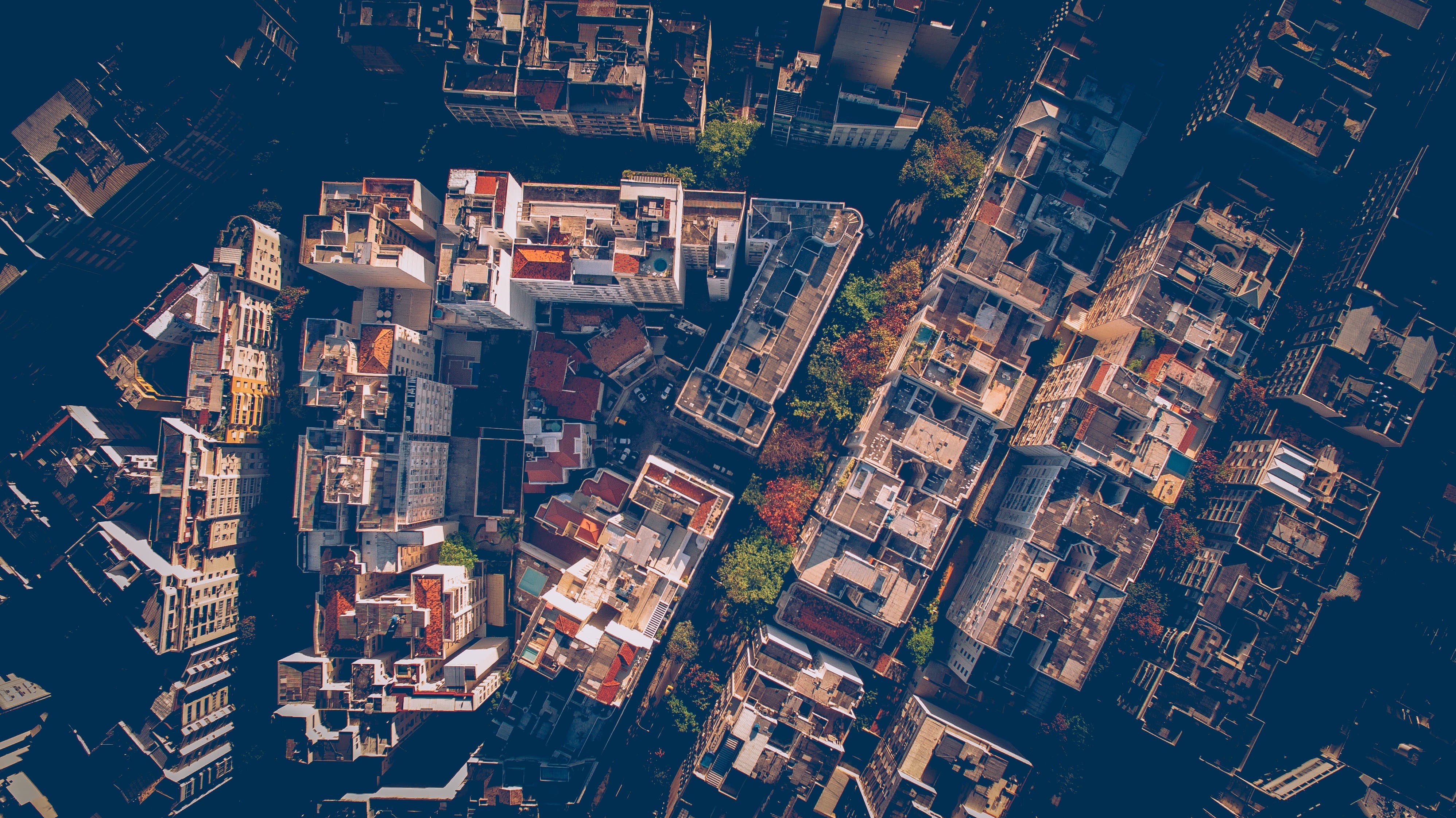 Aerial view of a dense city with buildings and trees HD Wallpaper