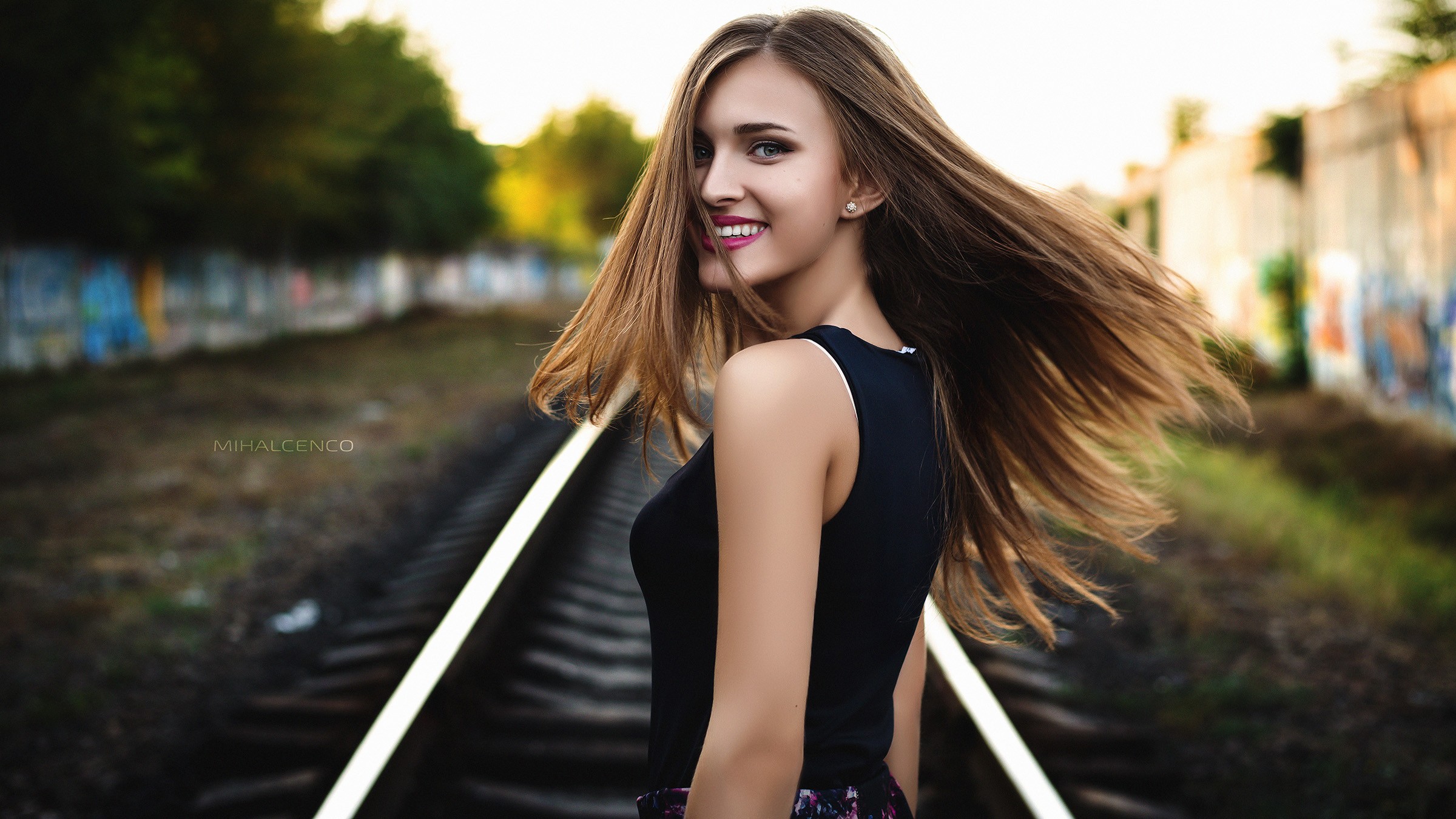 Woman with long hair smiling on train tracks HD Wallpaper