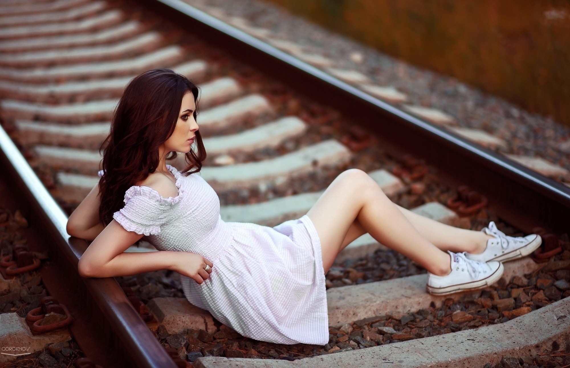 Woman in white dress lying on train tracks HD Wallpaper