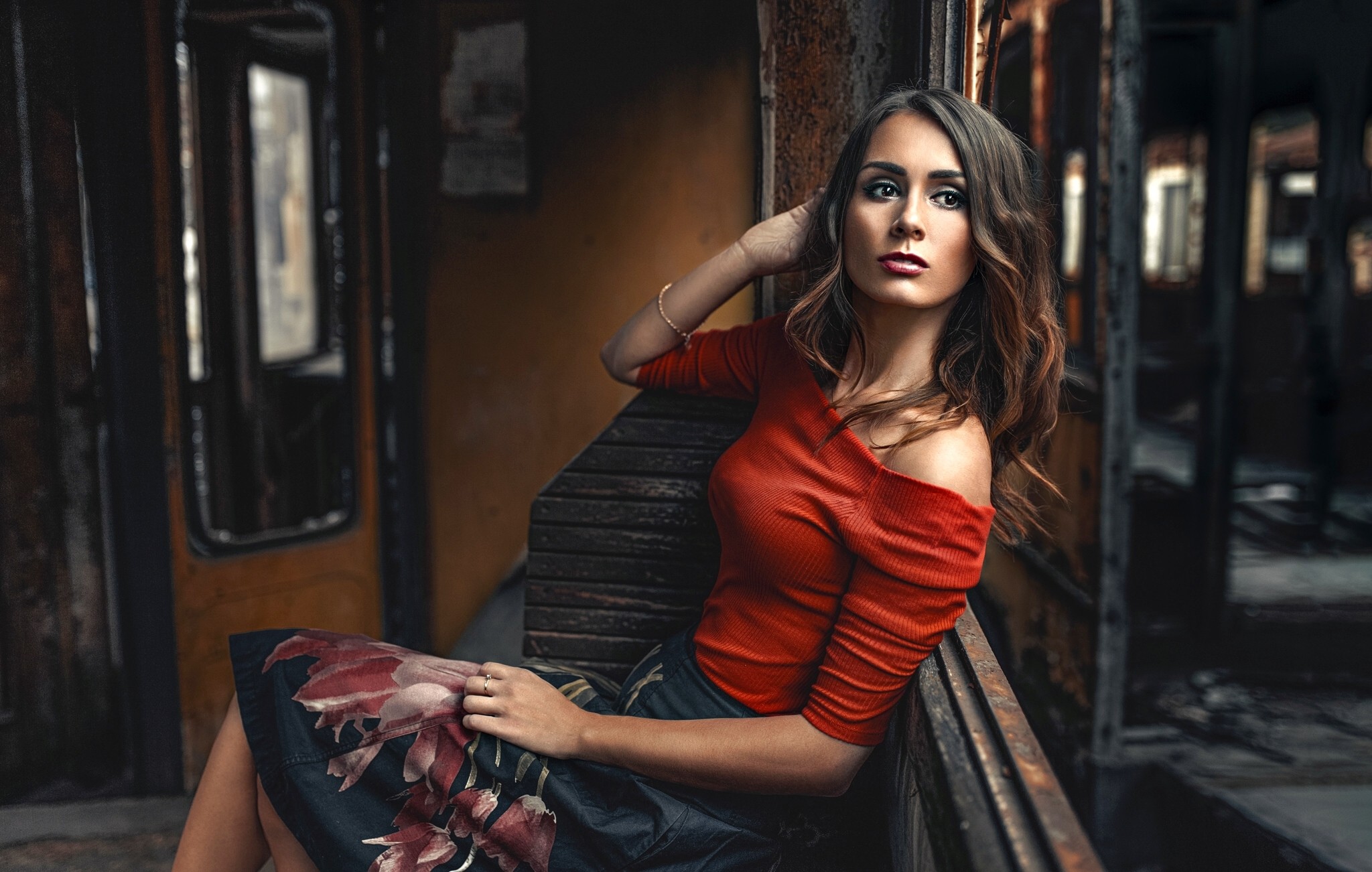 Woman in red top and floral skirt sitting in train car HD Wallpaper