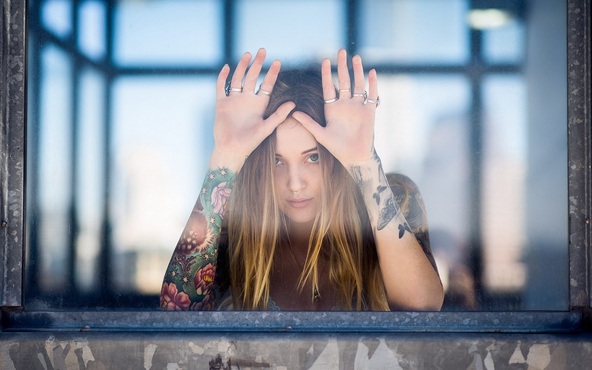 Woman with tattoos looking through a window HD Wallpaper