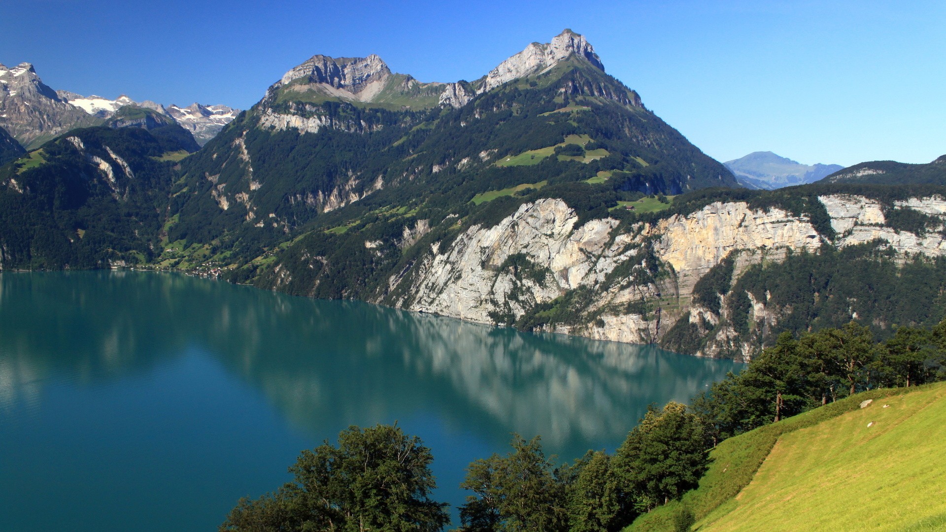 Turquoise lake surrounded by mountains and forests HD Wallpaper