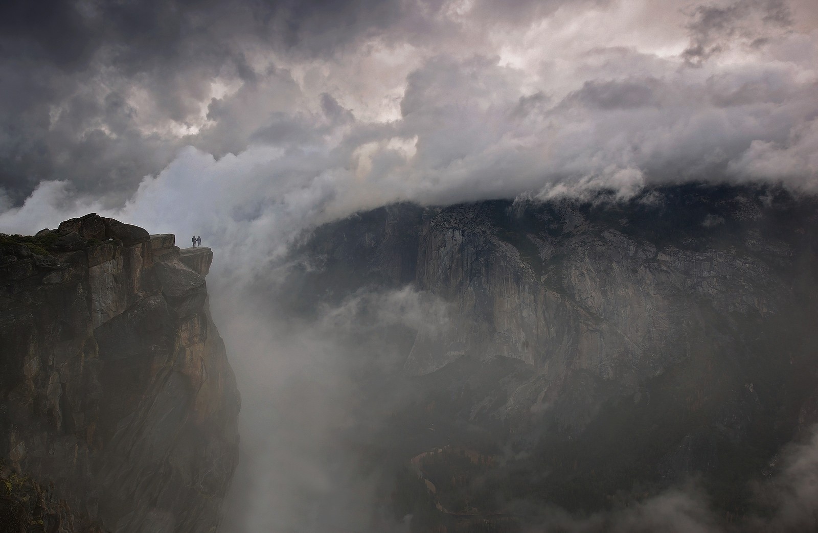 Couple on cliff edge in Yosemite National Park with mist HD Wallpaper