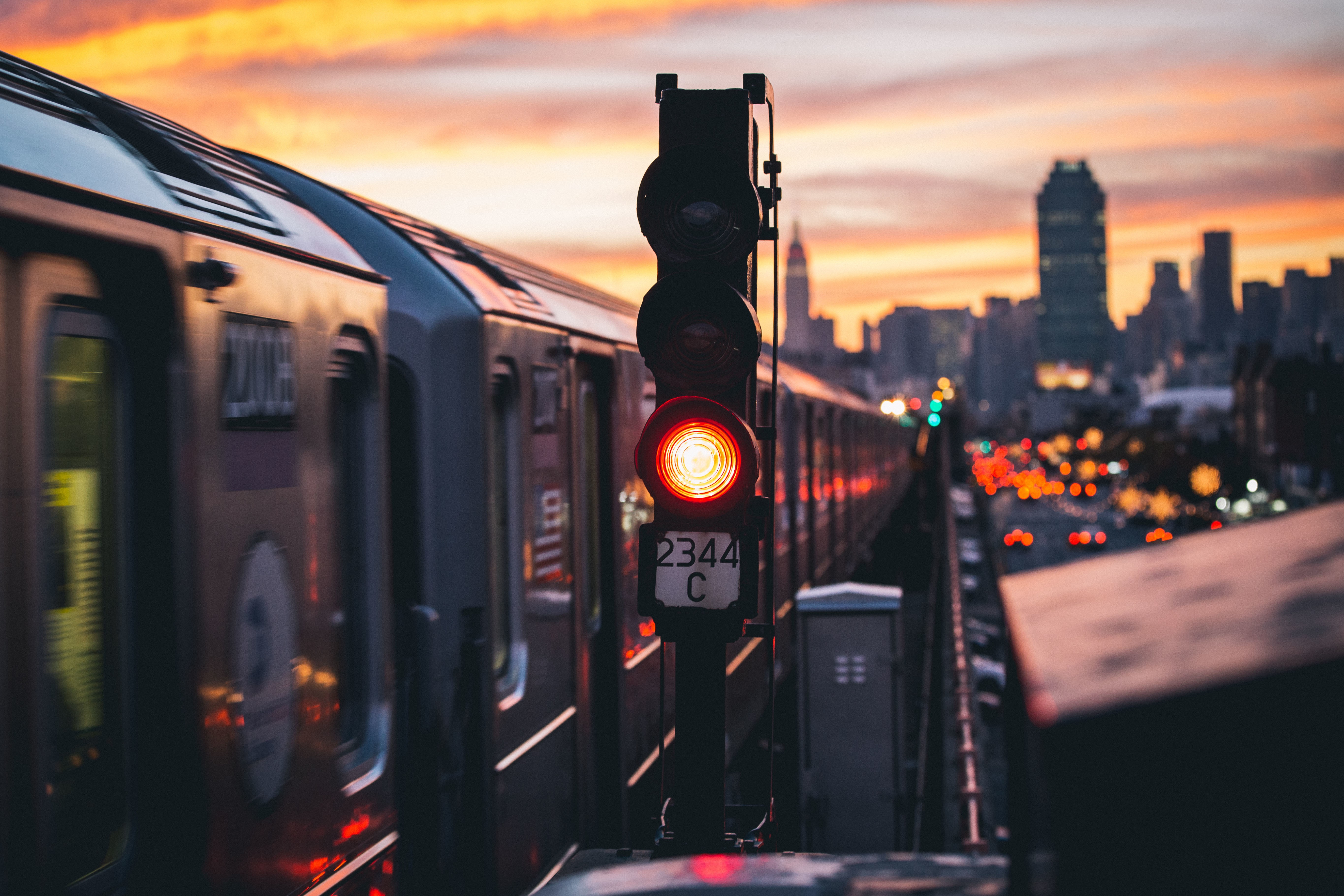 Train passing a traffic light at sunset in a cityscape HD Wallpaper