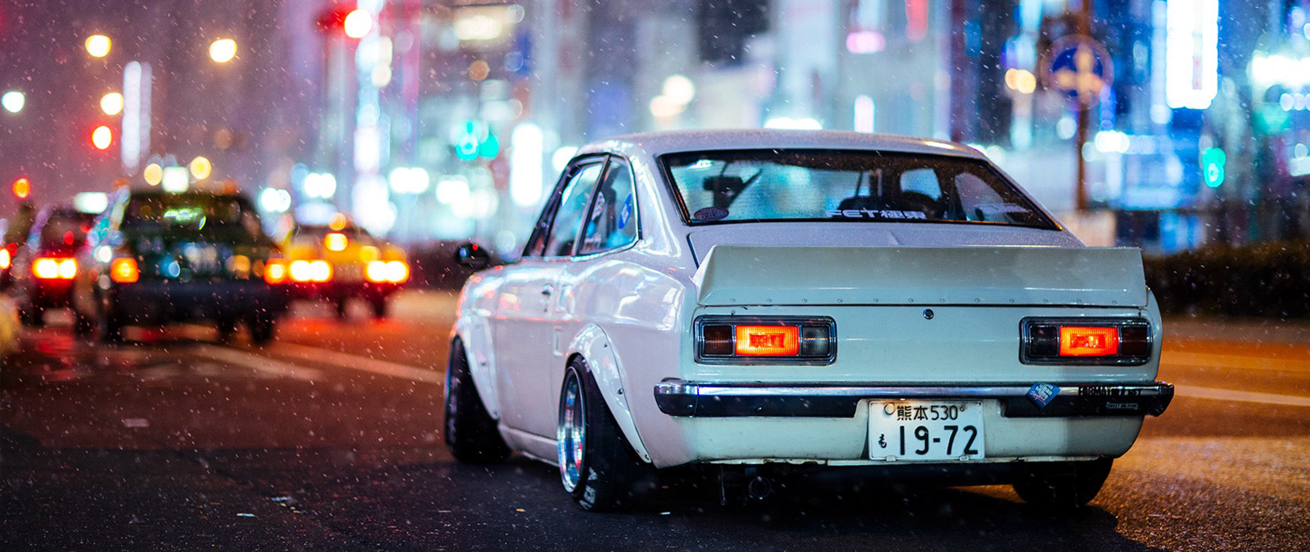 White modified car driving on a rainy city street at night HD Wallpaper