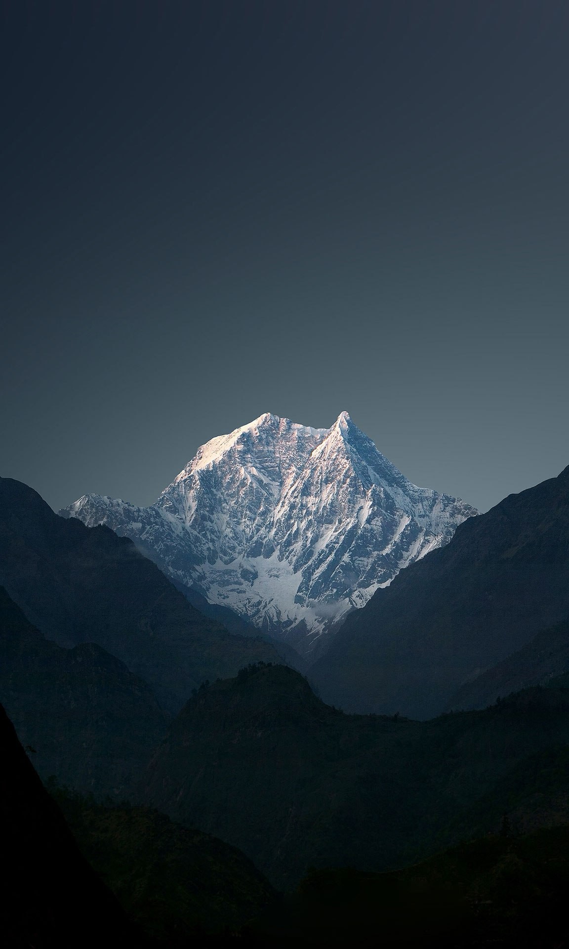 Snow-capped mountain peak under a dark sky HD Wallpaper