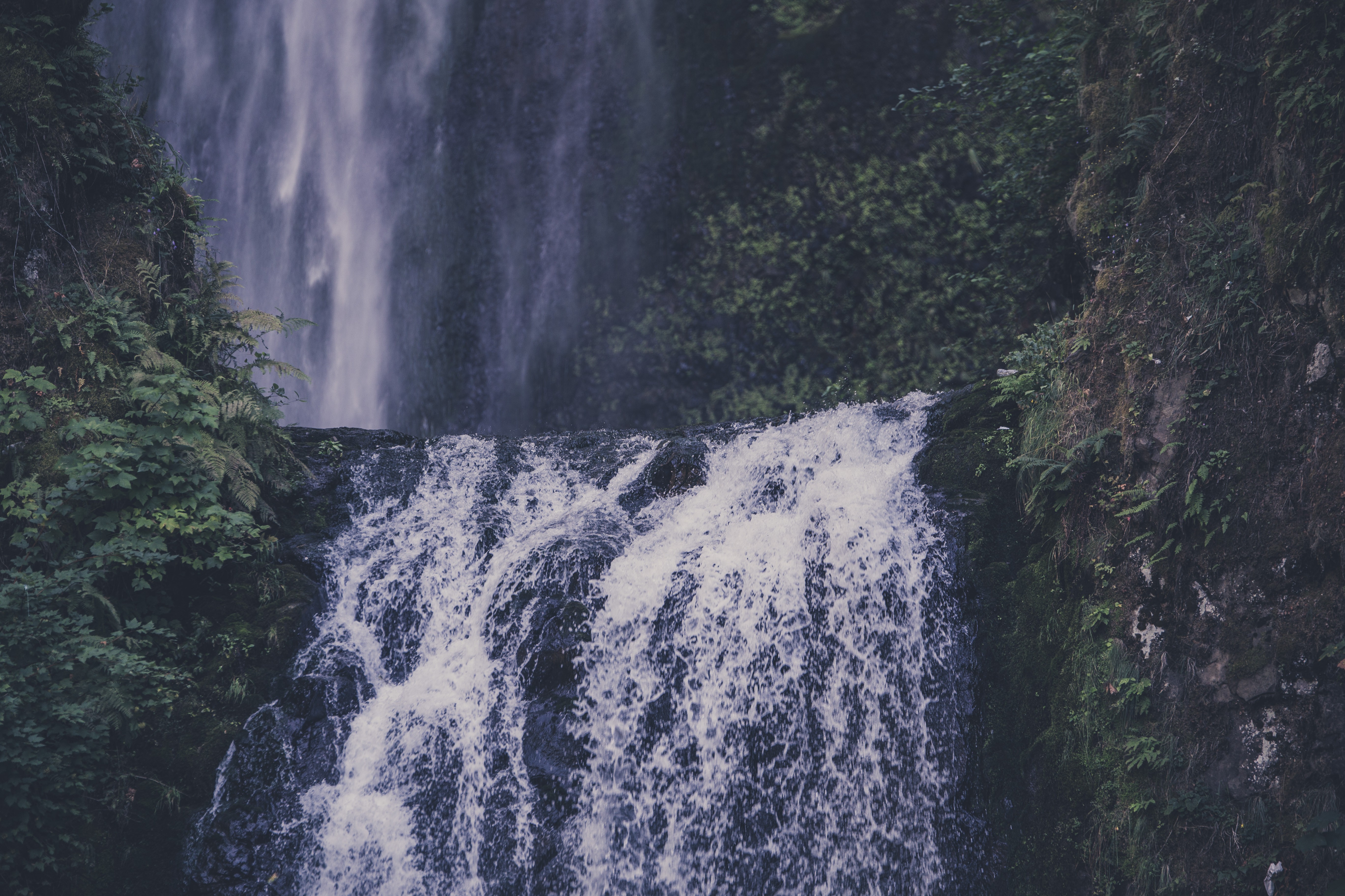 Waterfall cascading over rocks with lush greenery HD Wallpaper
