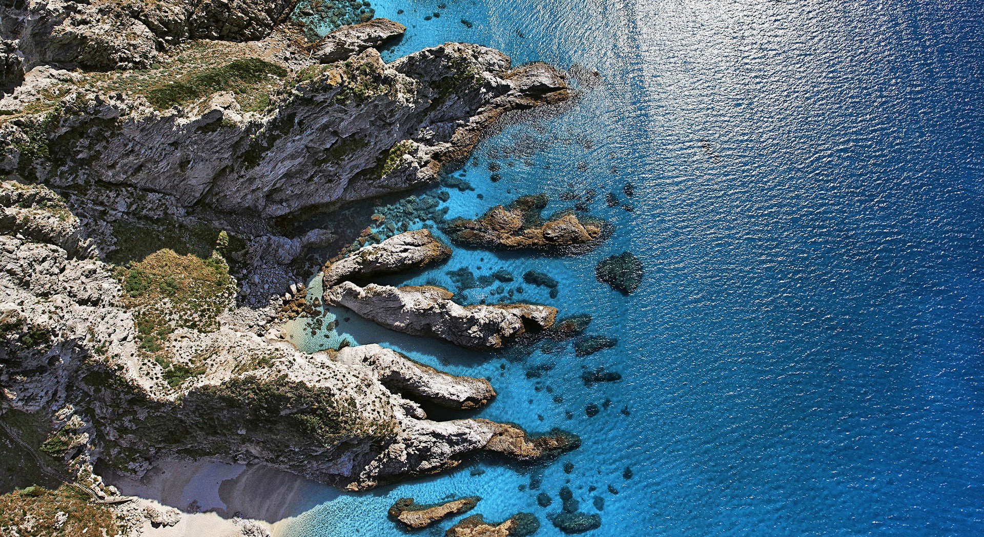 Aerial view of rocky coastline and turquoise sea HD Wallpaper
