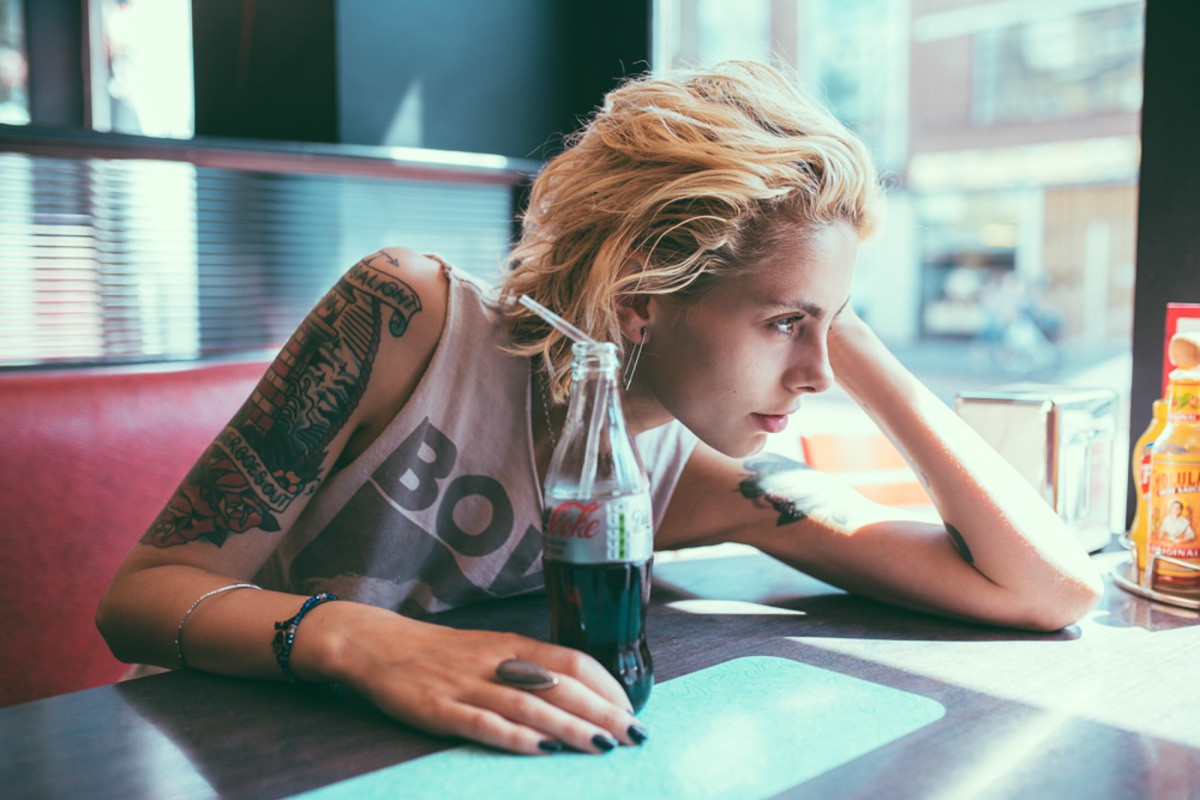 Woman with tattoos and Coca-Cola bottle in a diner HD Wallpaper