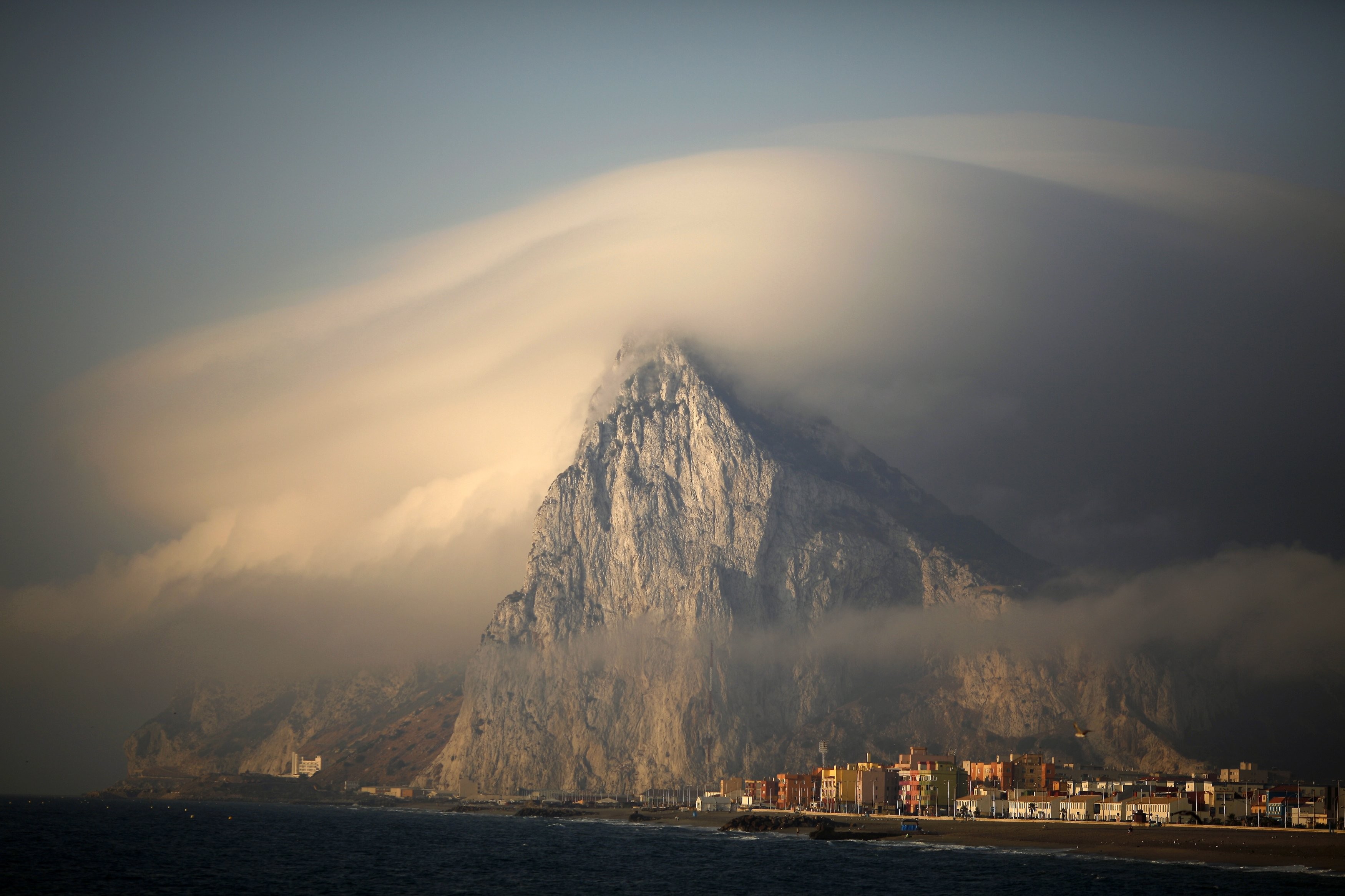 Gibraltar mountain shrouded in clouds over the coast HD Wallpaper
