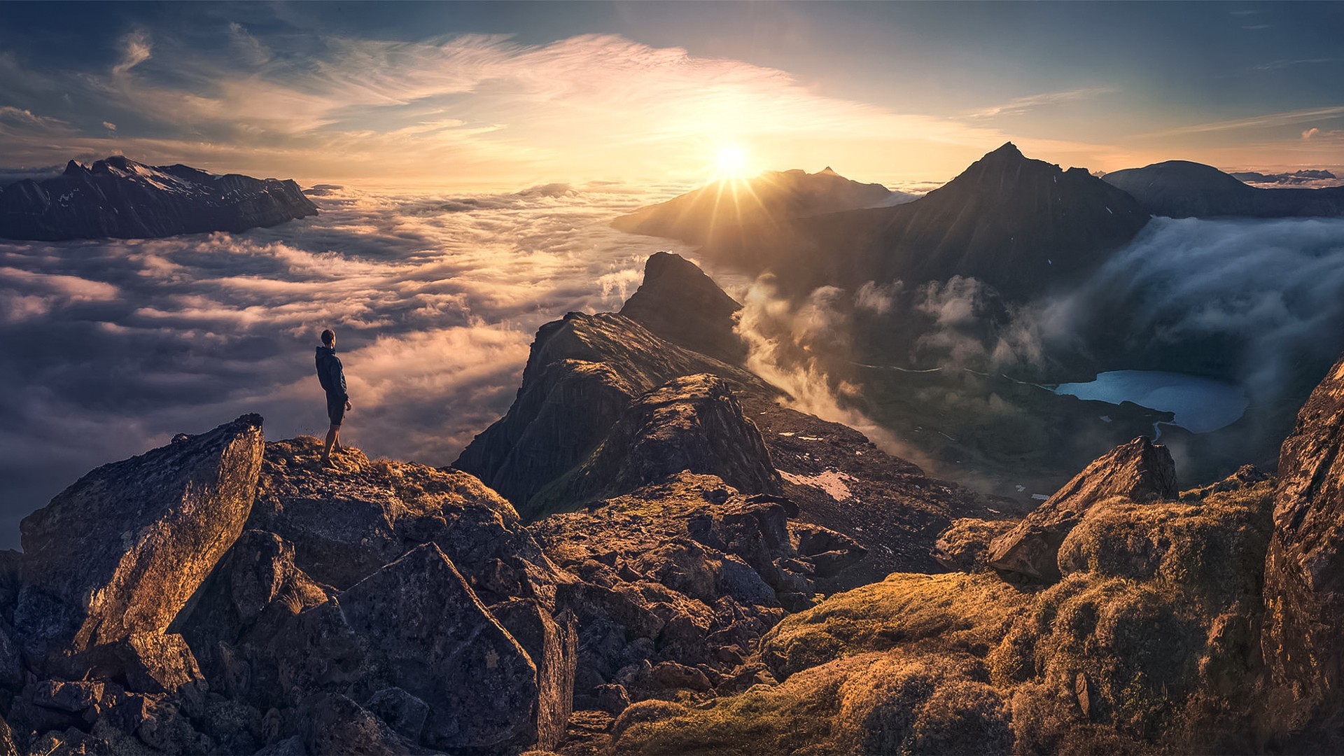 Man standing on mountain peak above clouds at sunset HD Wallpaper