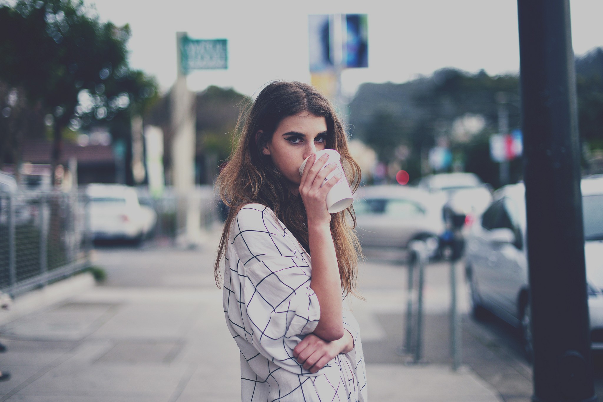 Woman drinking from a cup on a street HD Wallpaper