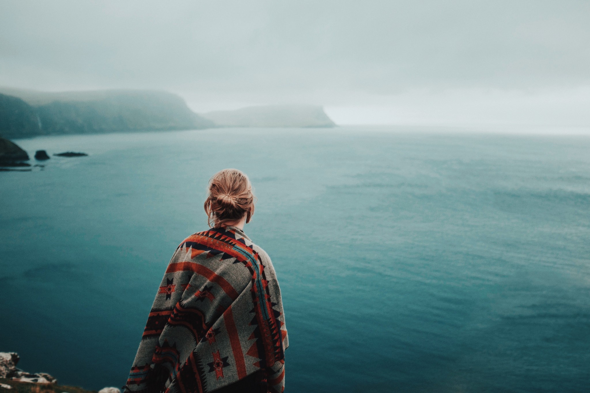 Woman in poncho looking at the ocean HD Wallpaper