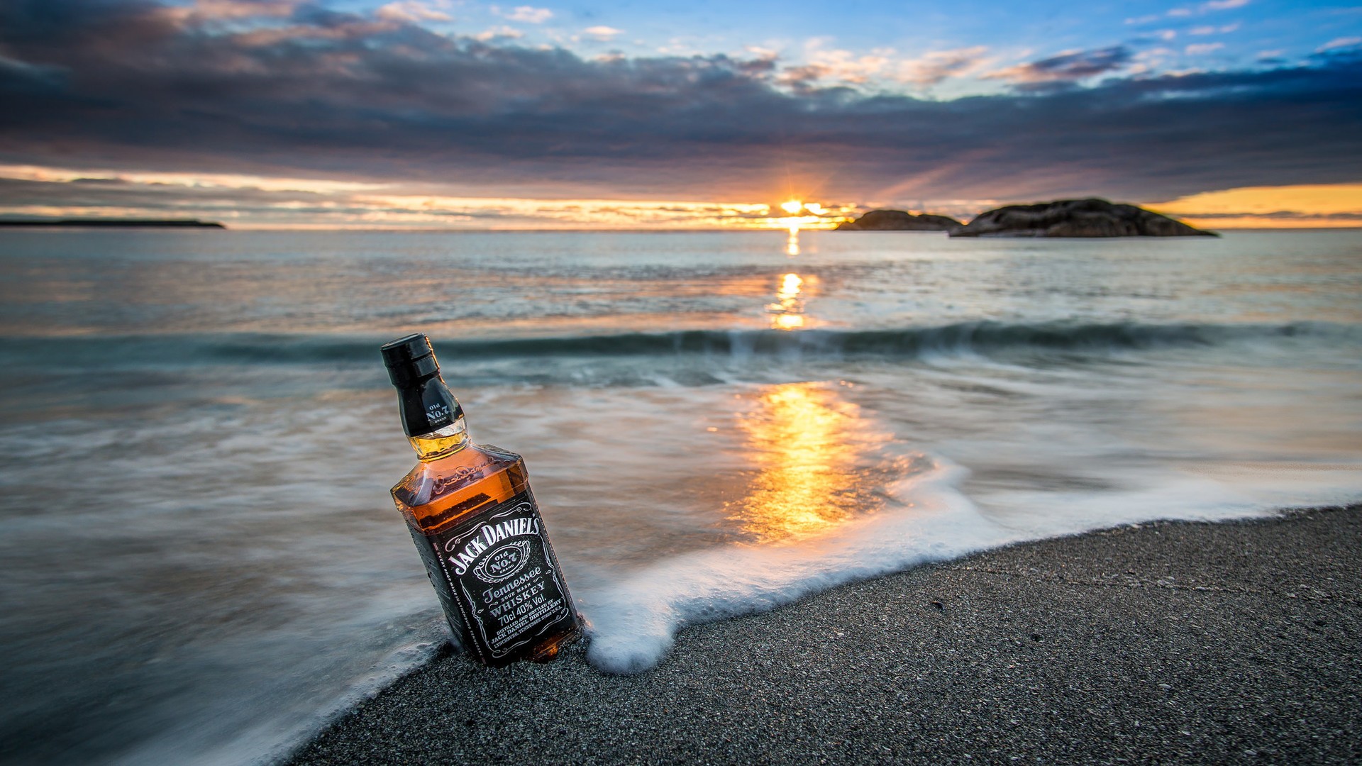Jack Daniels bottle on a beach at sunset HD Wallpaper