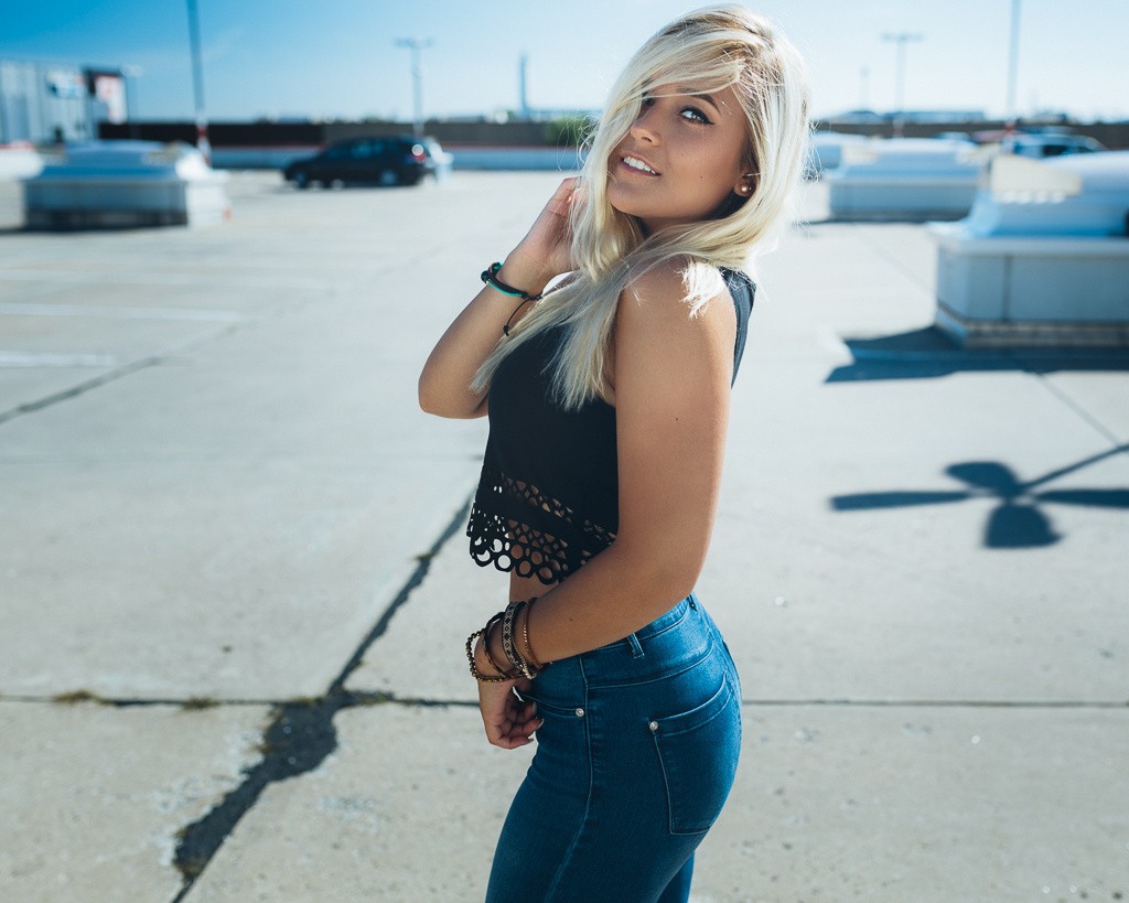 Woman in jeans and black top smiling HD Wallpaper