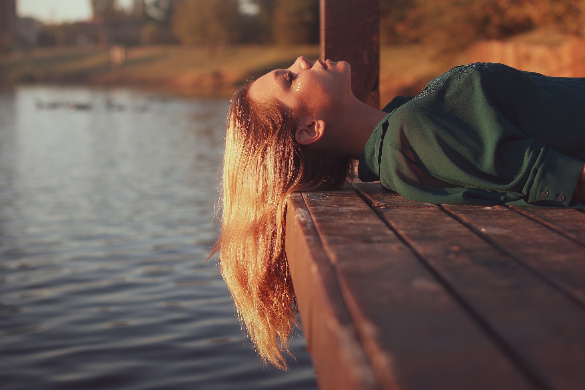 Woman lying on a pier by the water HD Wallpaper