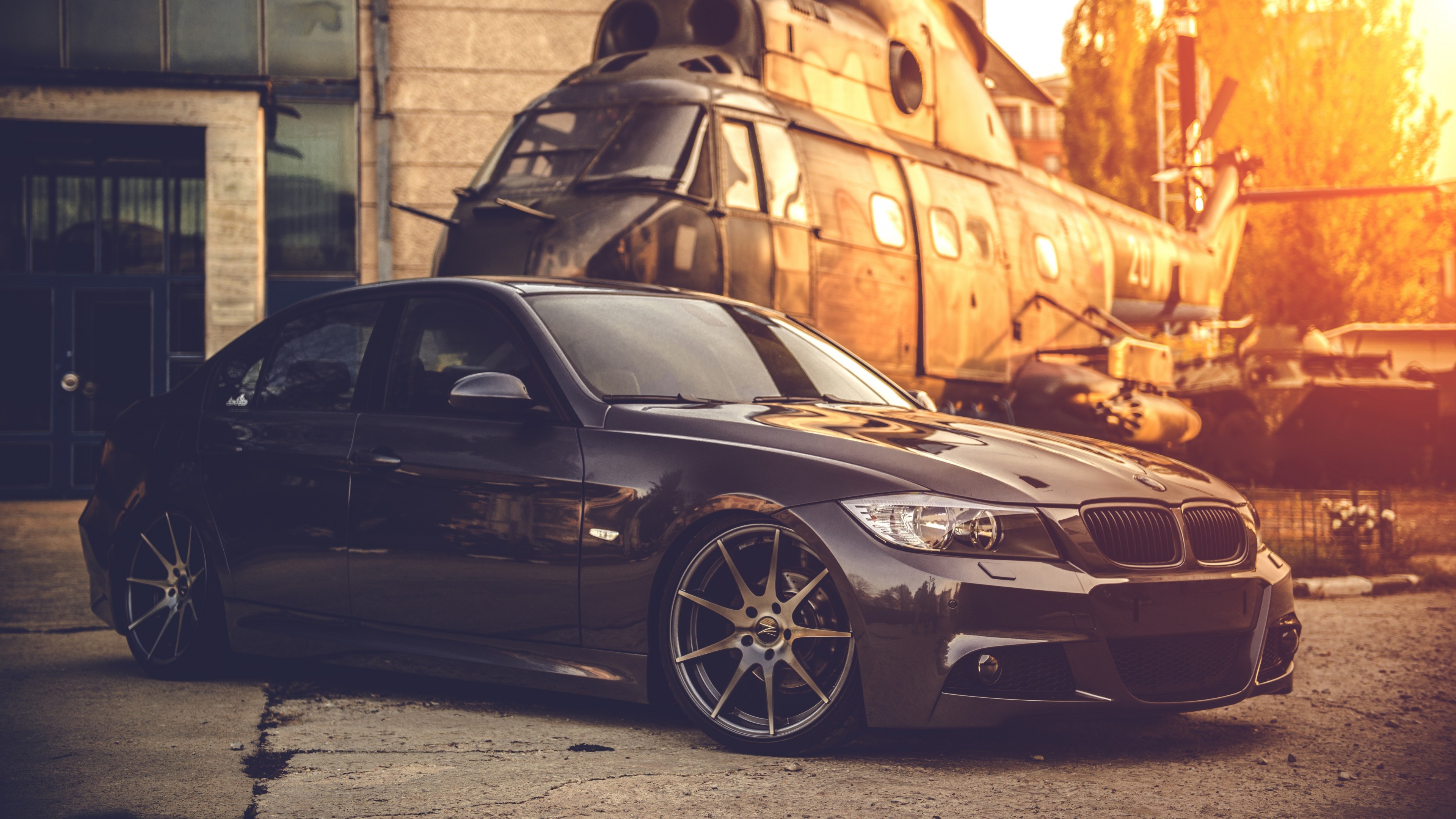 BMW E90 Sedan parked near a helicopter HD Wallpaper
