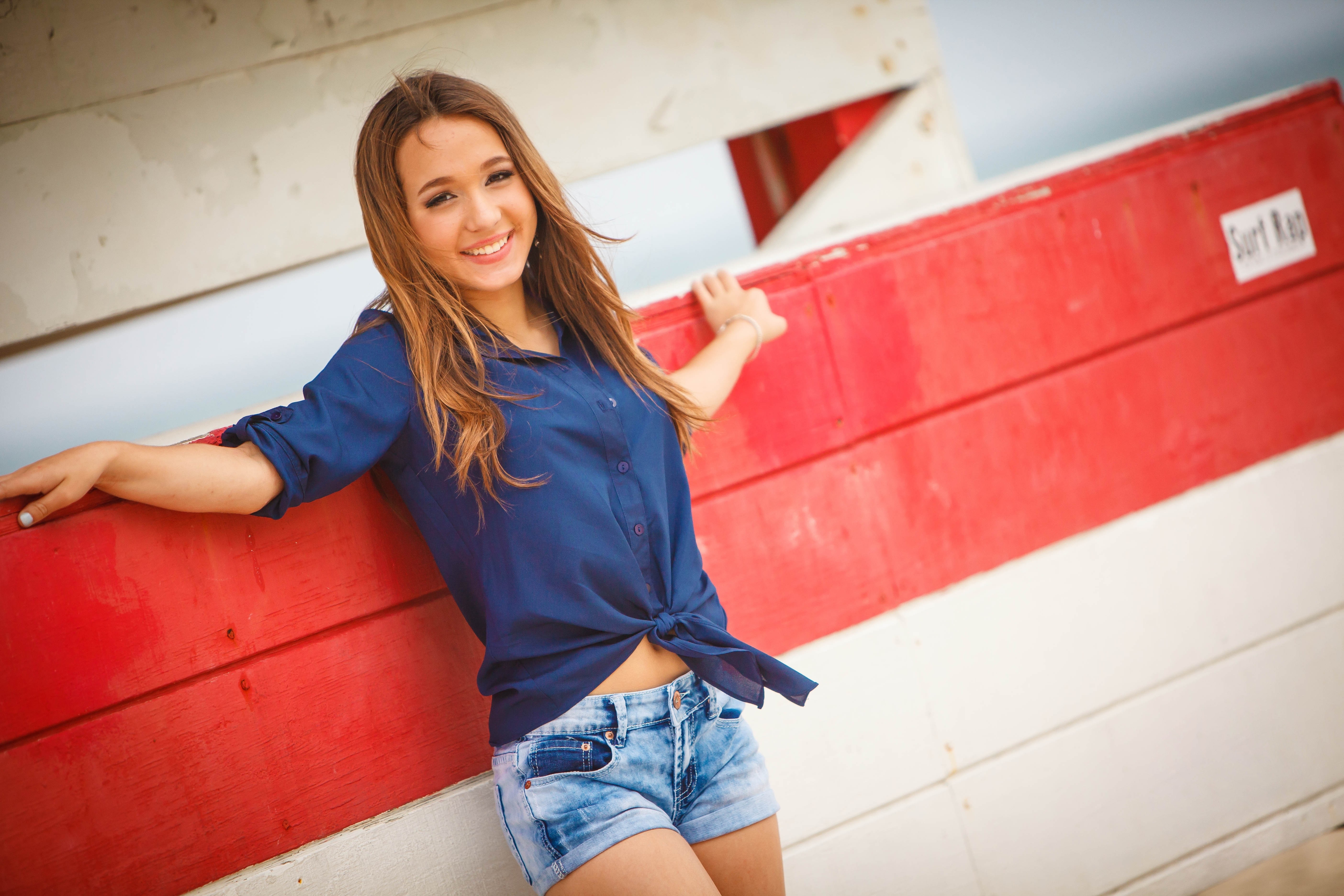 Young woman in blue shirt and denim shorts HD Wallpaper