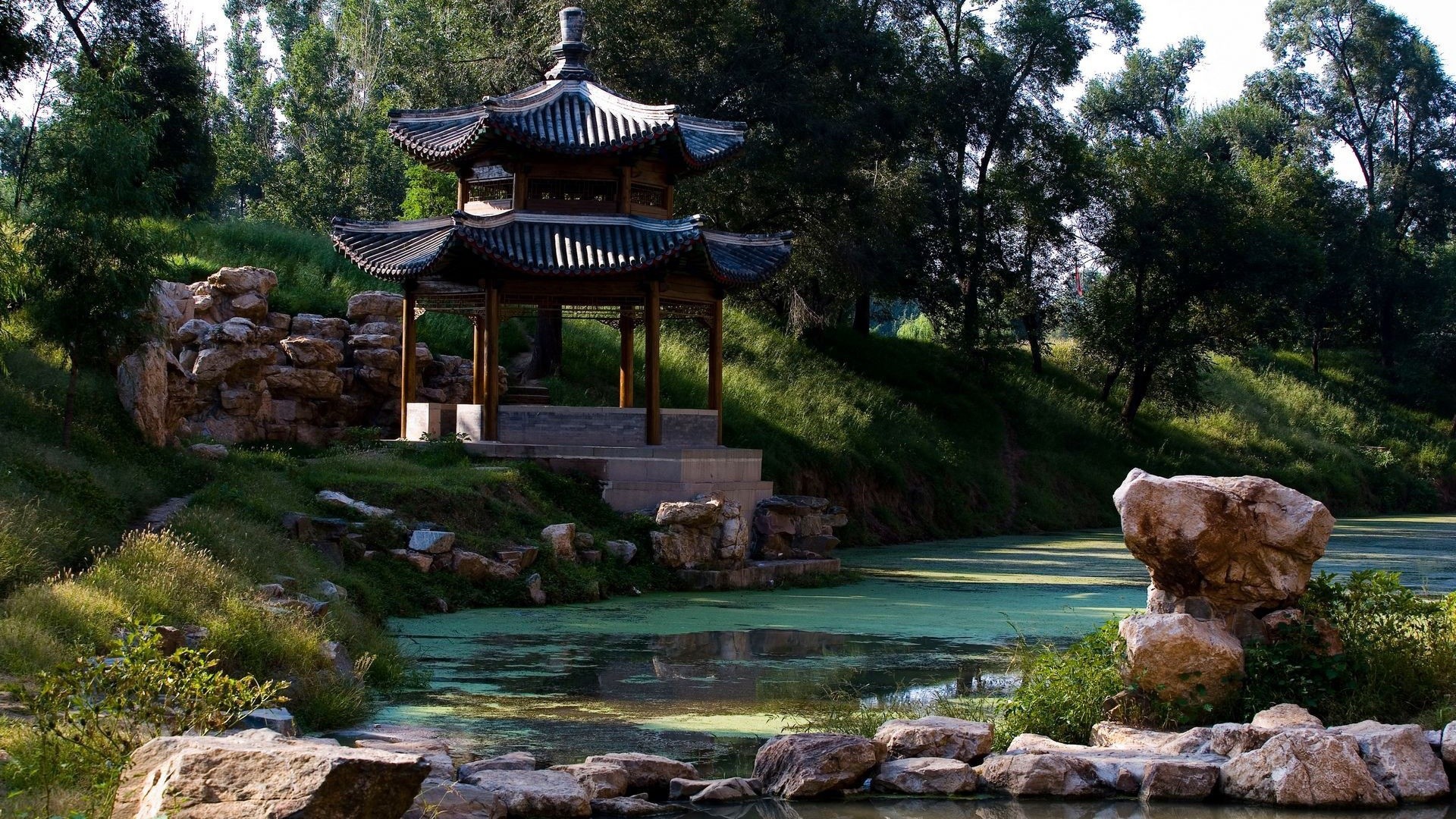 Pagoda by a tranquil pond in a park HD Wallpaper