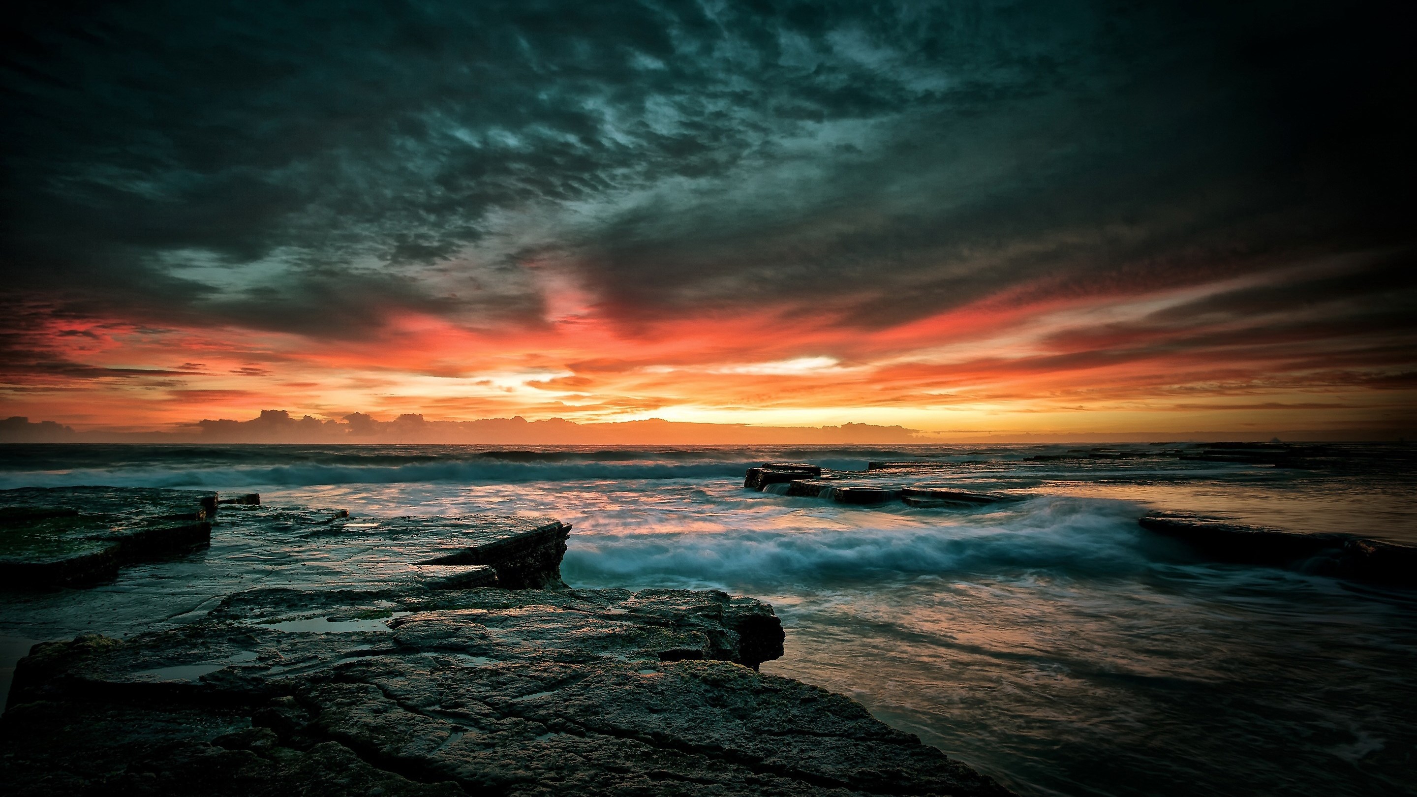 Ocean waves crash on rocky shore at sunset HD Wallpaper