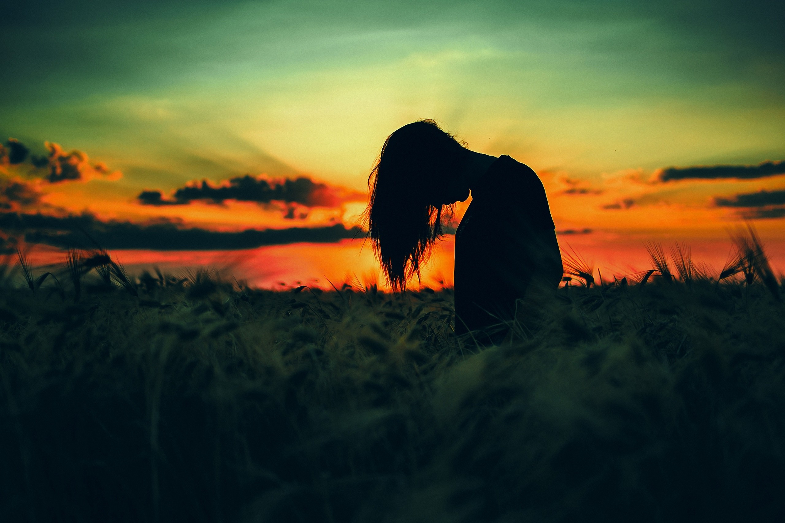 Silhouette of a woman in a field at sunset HD Wallpaper